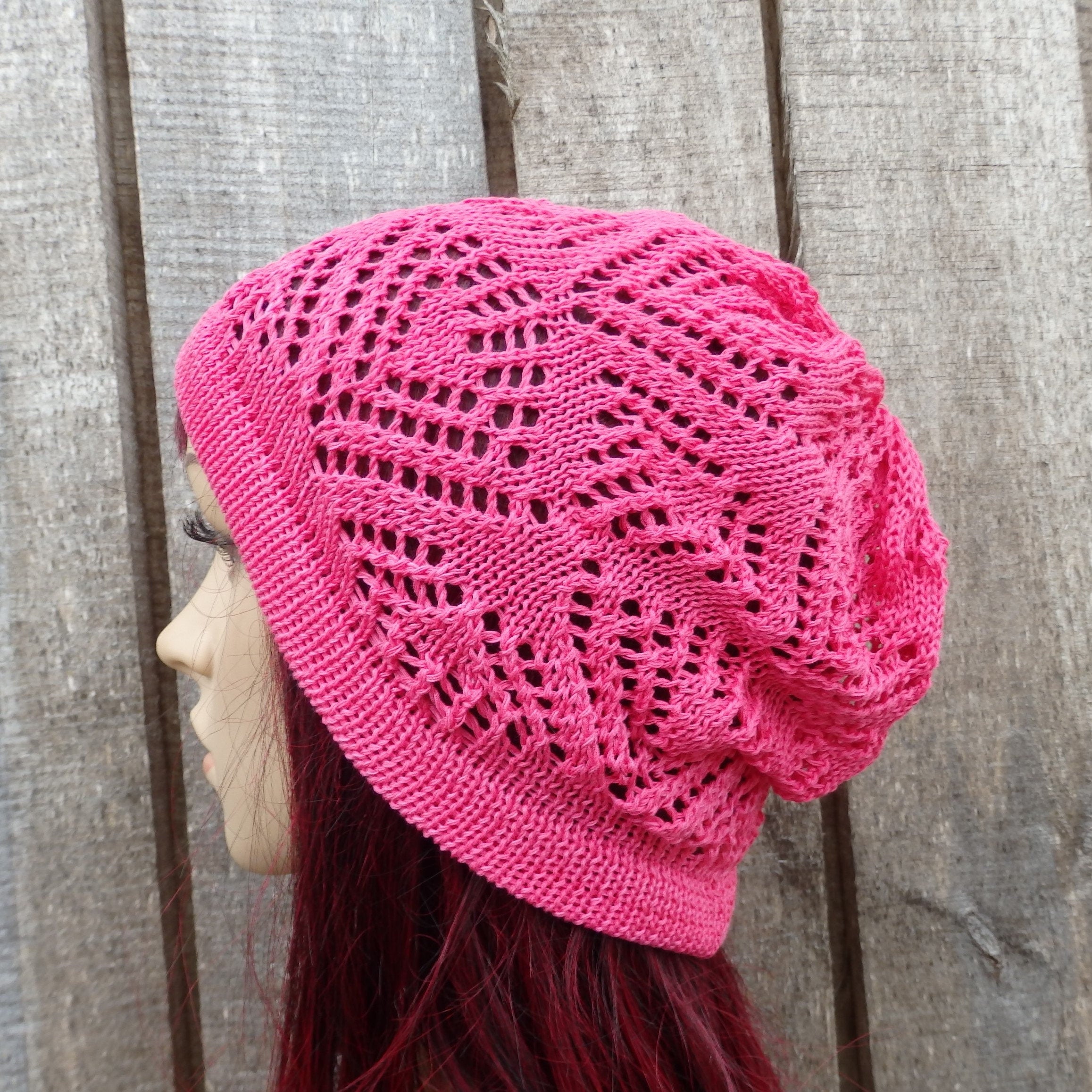 Pink knitted hat worn by a person against a wooden background