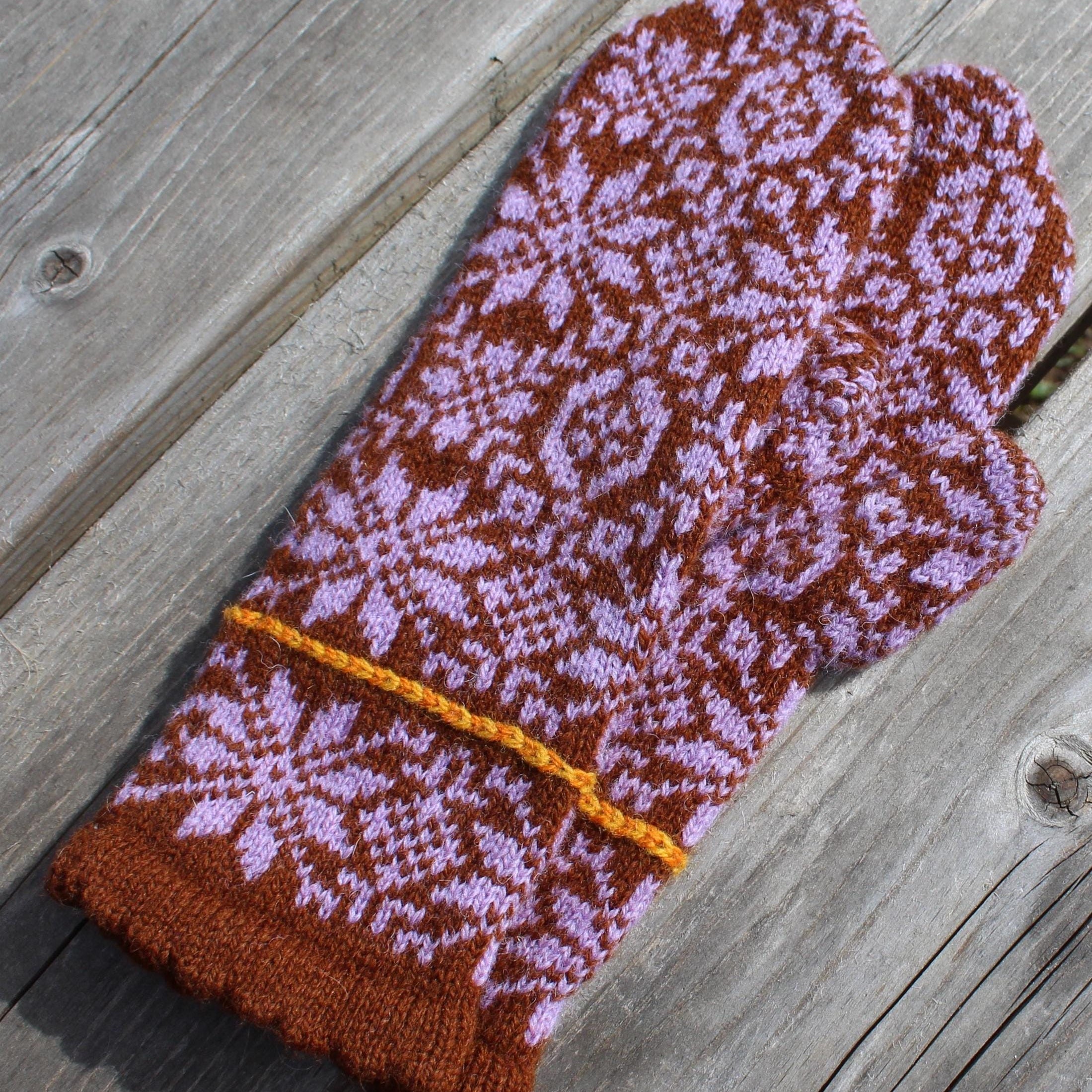 Pair of knitted mittens with a floral pattern on a wooden surface