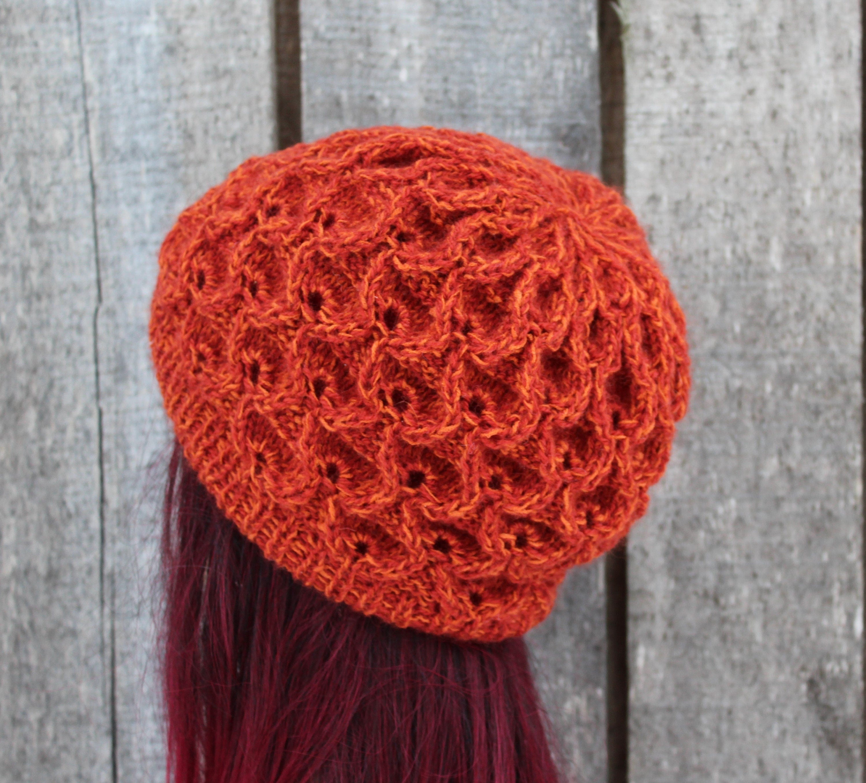 Orange knitted hat with tassel on a wooden background