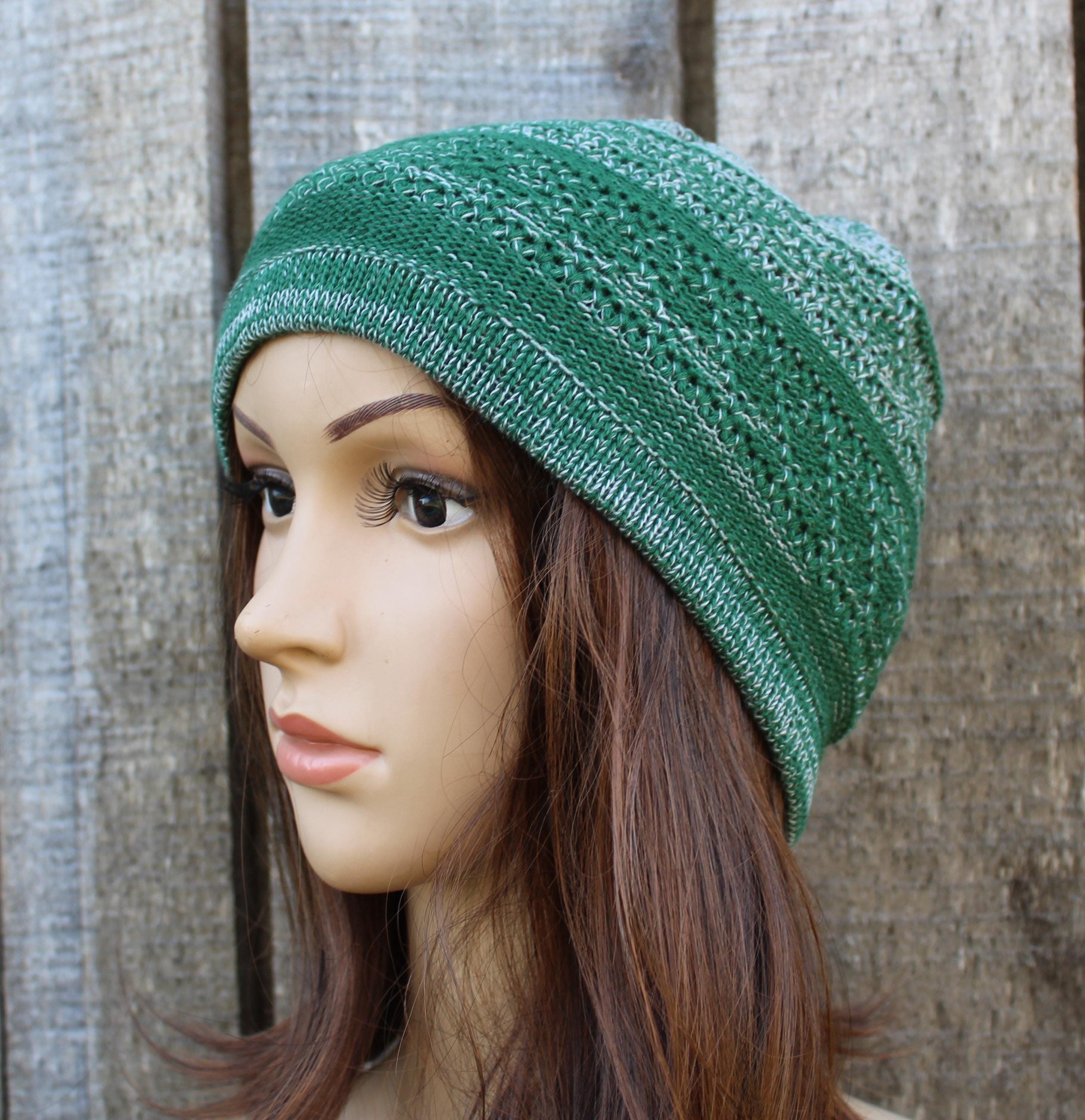 Green knitted beanie on a mannequin head against a wooden background