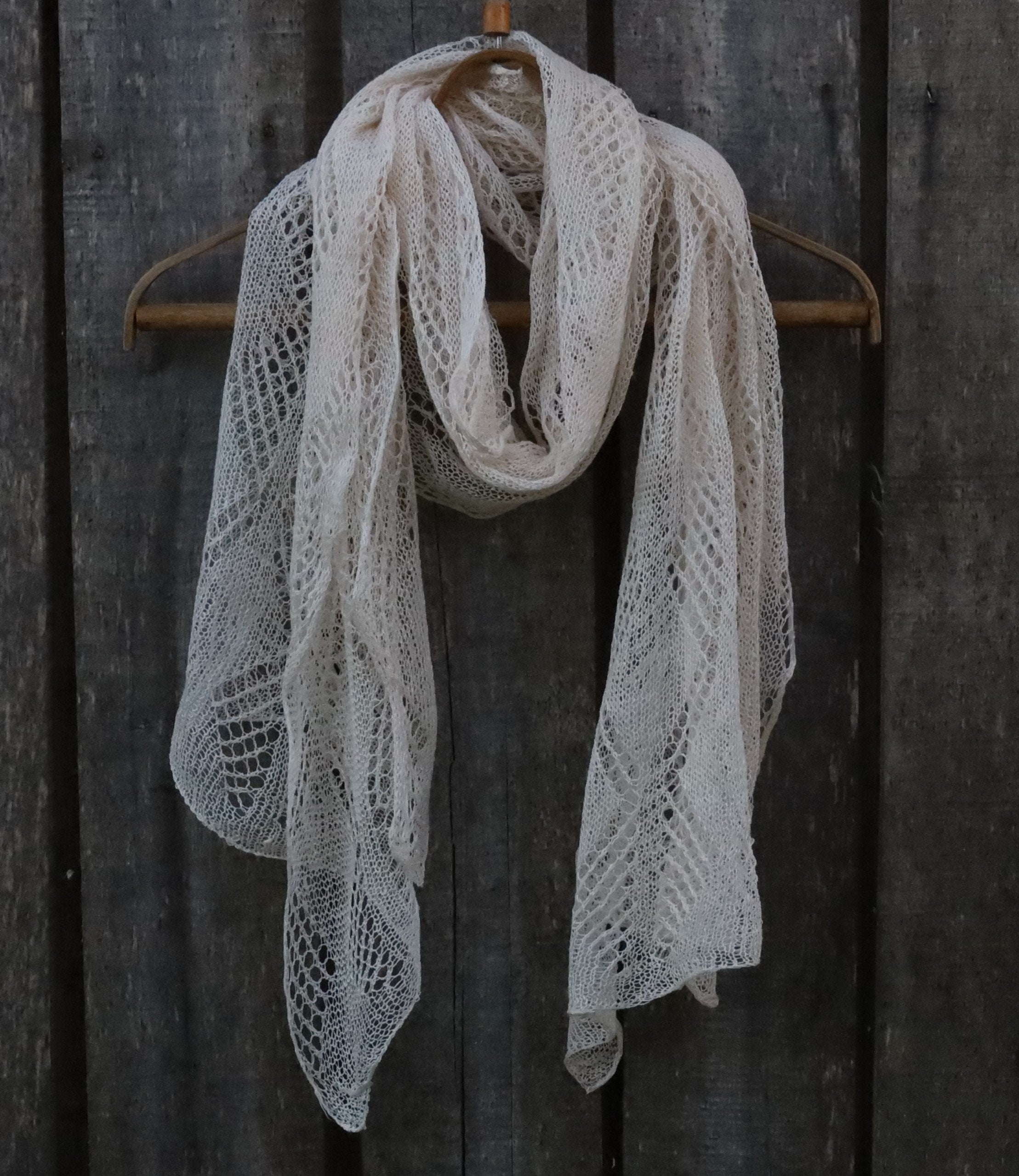 Knitted scarf draped over a wooden hanger against a dark wooden background