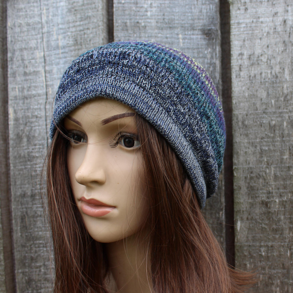 Mannequin head wearing a blue knit beanie against a wooden fence background