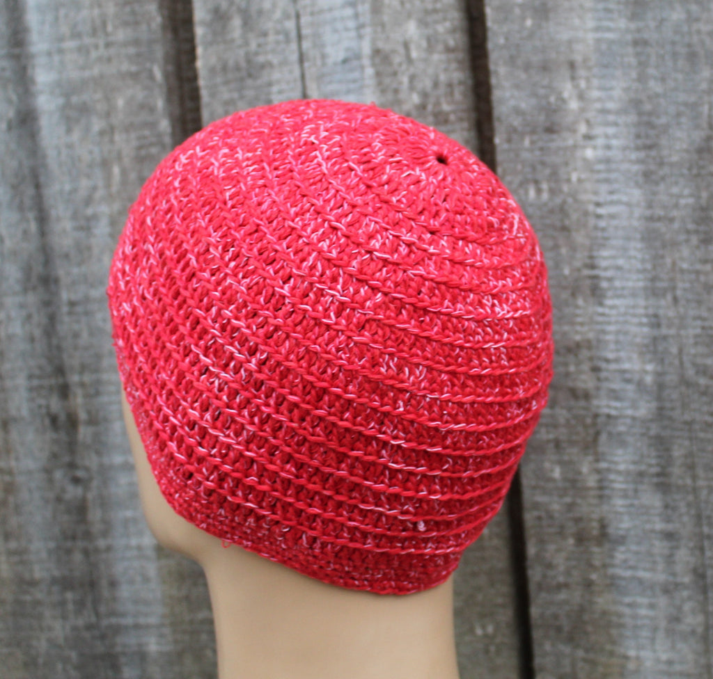 Red knitted hat on a mannequin head against a wooden background