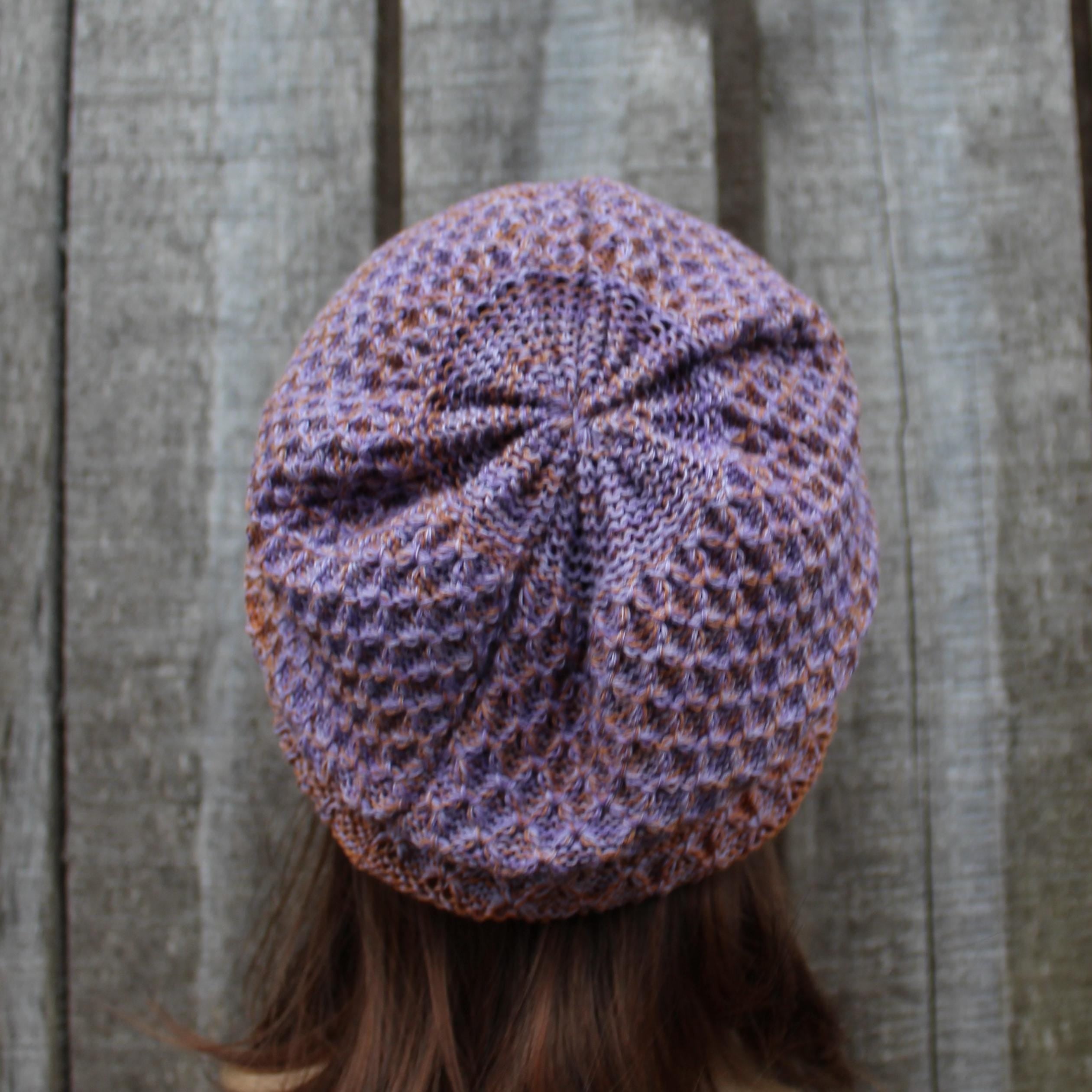 Knitted purple and brown beanie on a wooden background
