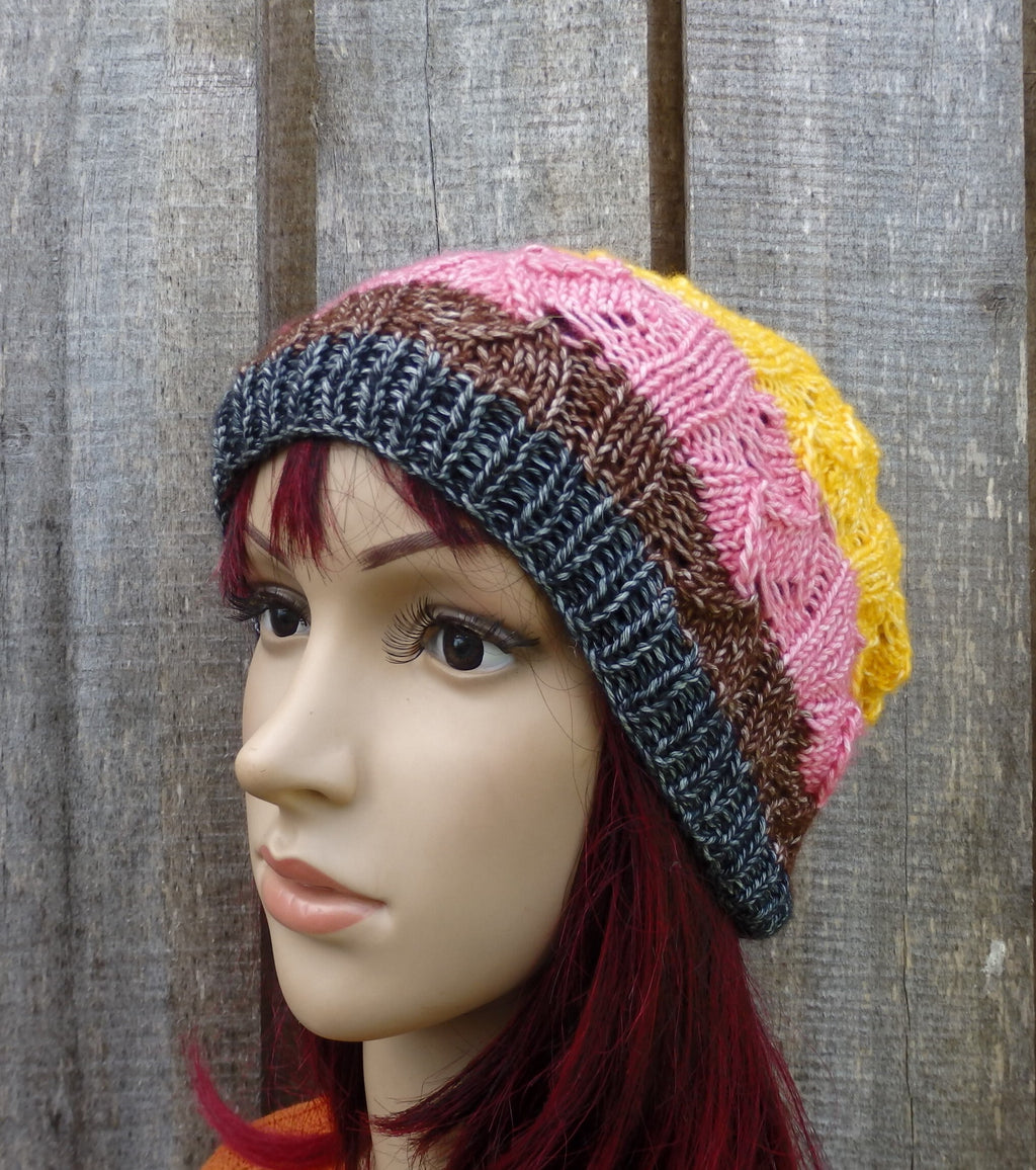 Mannequin head wearing a colorful striped knit hat against a wooden background