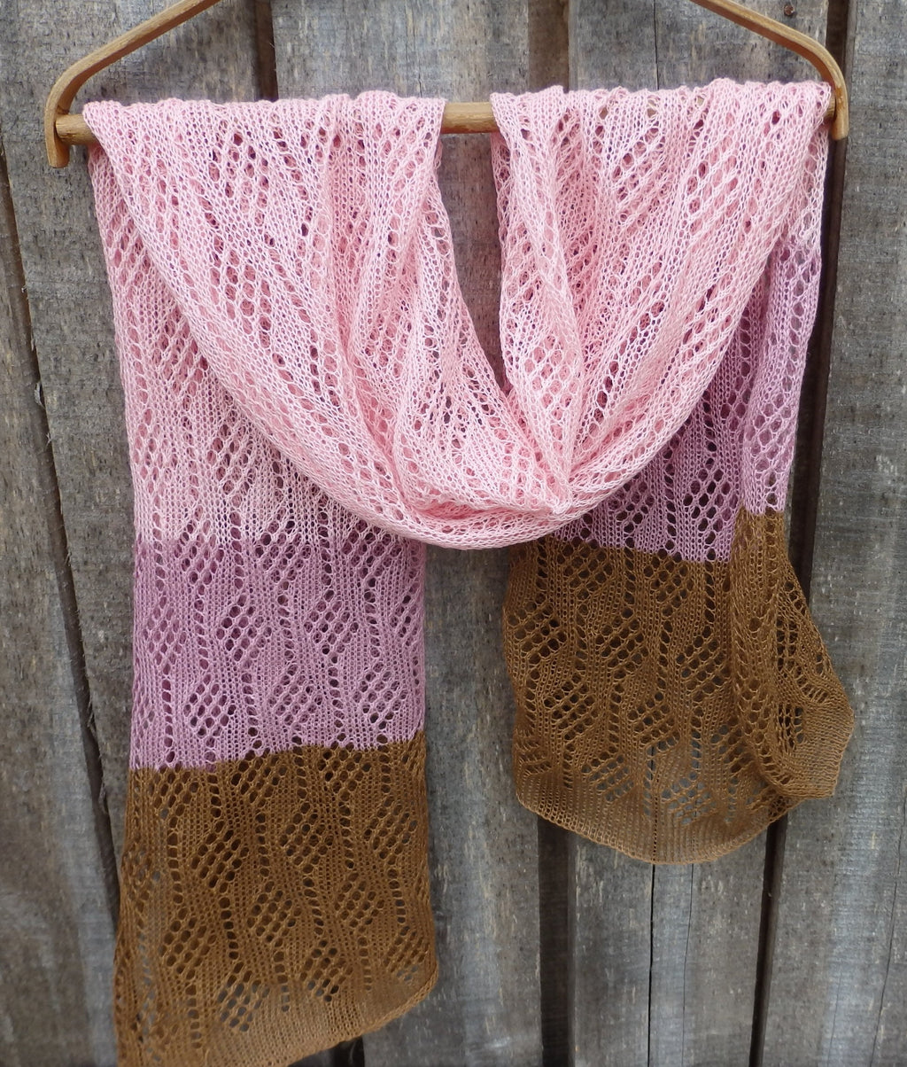Pink and brown knitted scarf on a wooden hanger against a wooden background