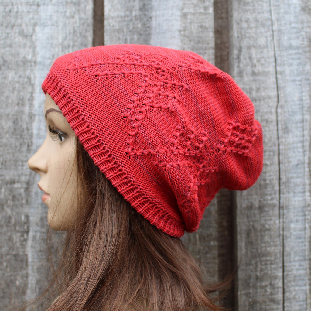 Person wearing a red knitted beanie against a wooden background