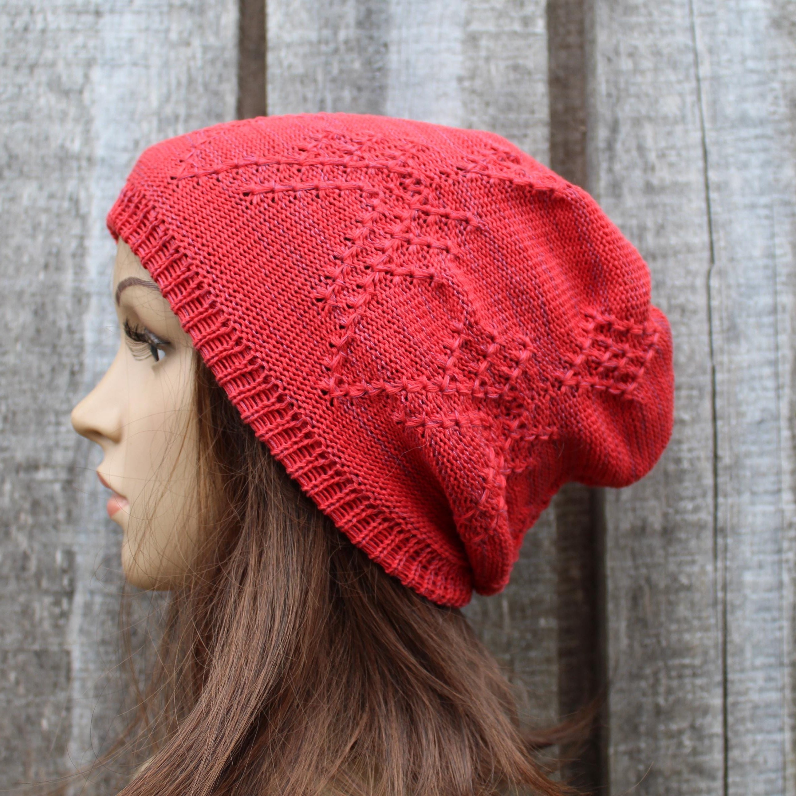 Person wearing a red knitted beanie against a wooden background