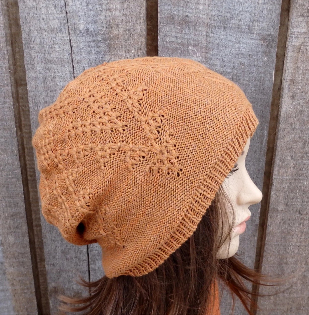 Brown knitted beanie worn by a person against a wooden background