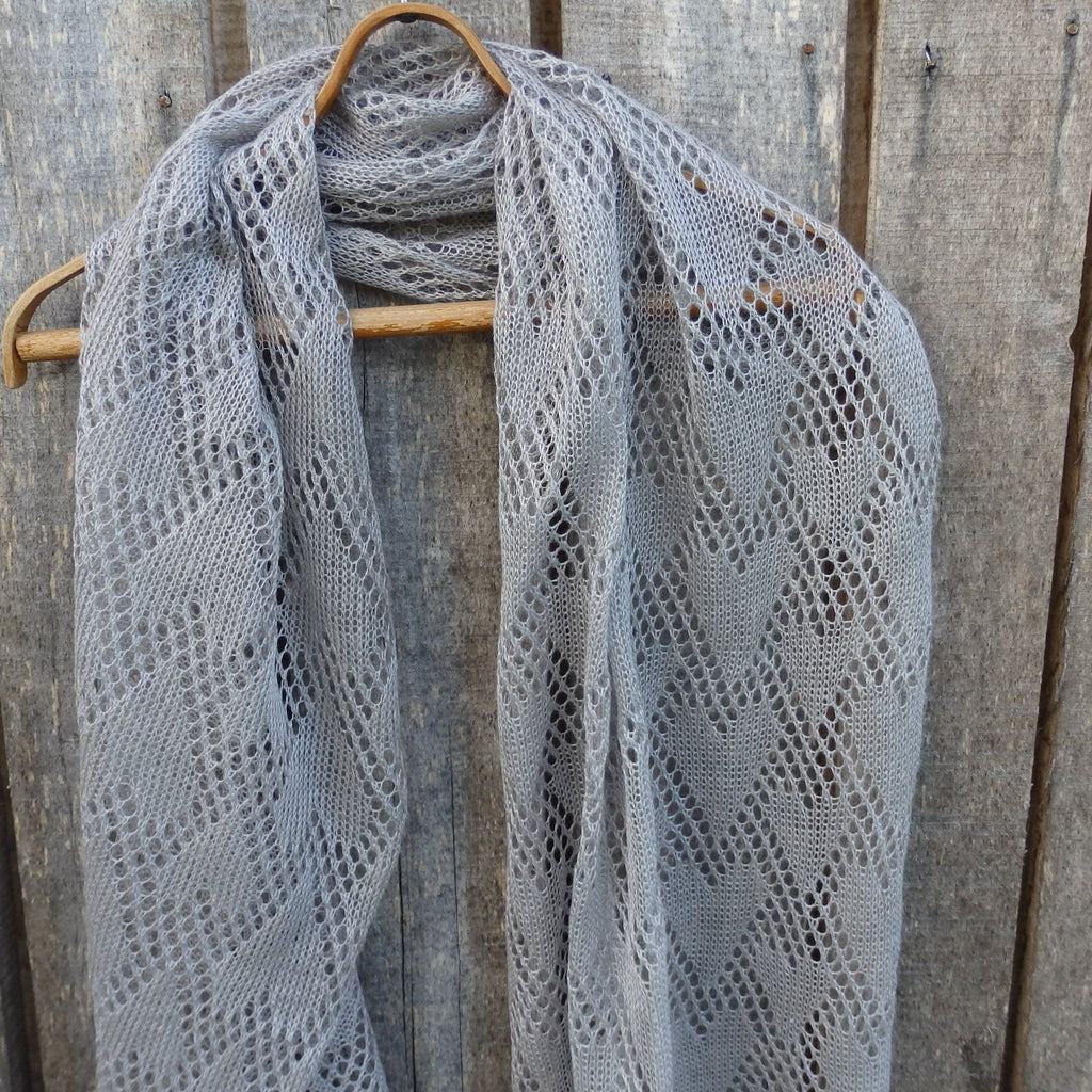 Linen shawl draped over a wooden hanger against a wooden background