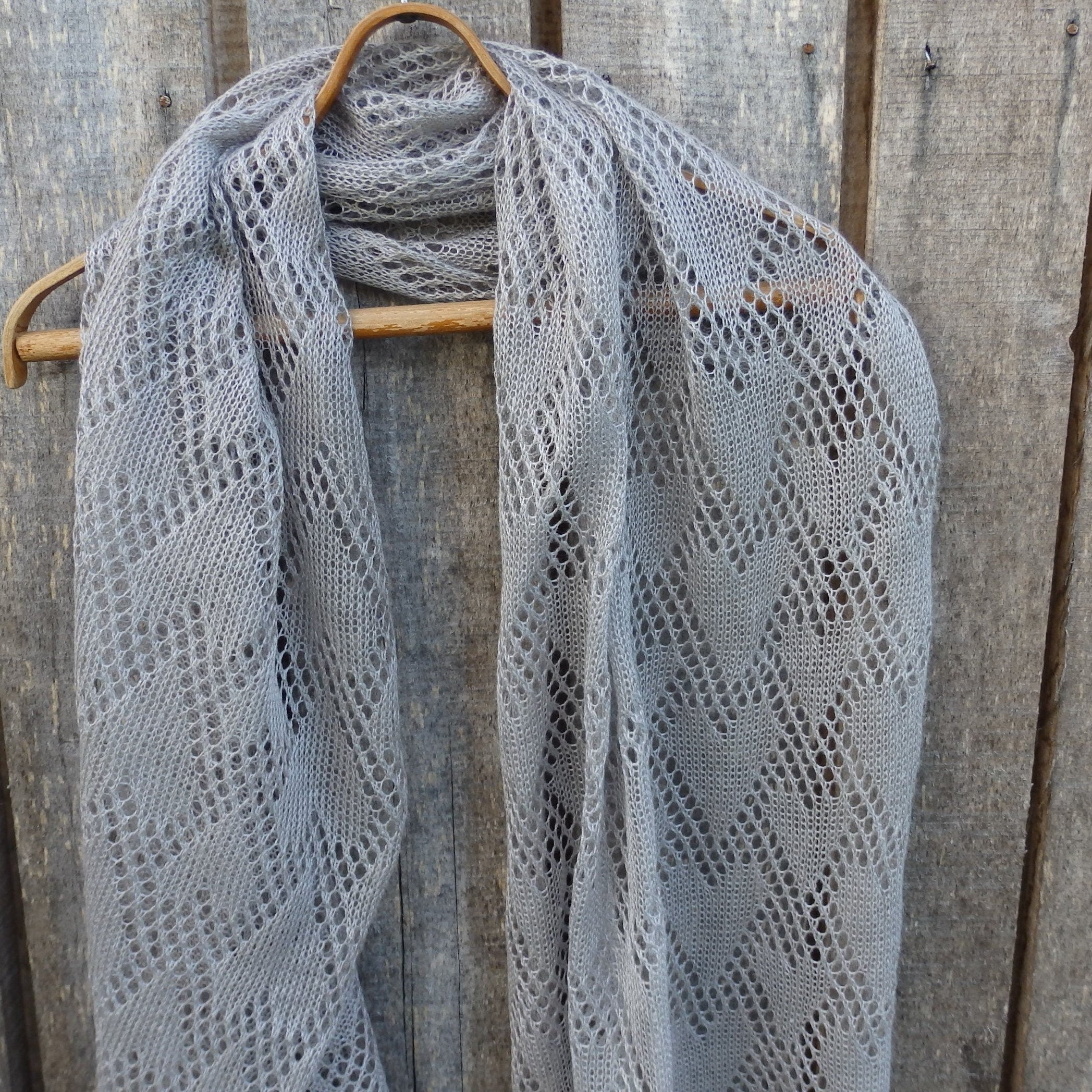 Linen shawl draped over a wooden hanger against a wooden background