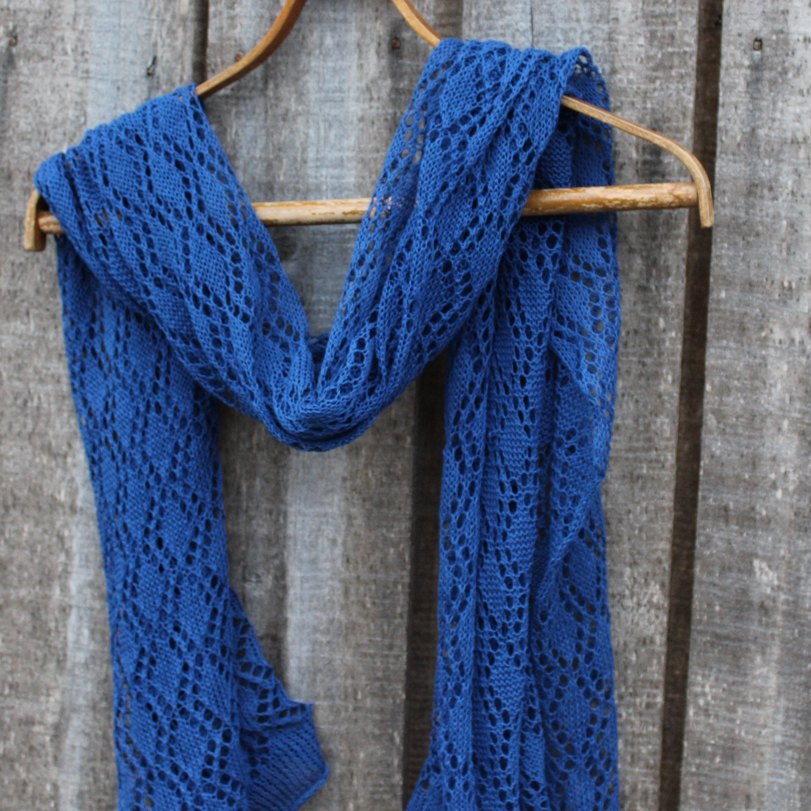 Blue knitted scarf on a wooden hanger against a wooden background