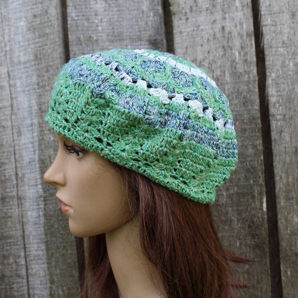 Green crocheted beanie on a mannequin head against a wooden background