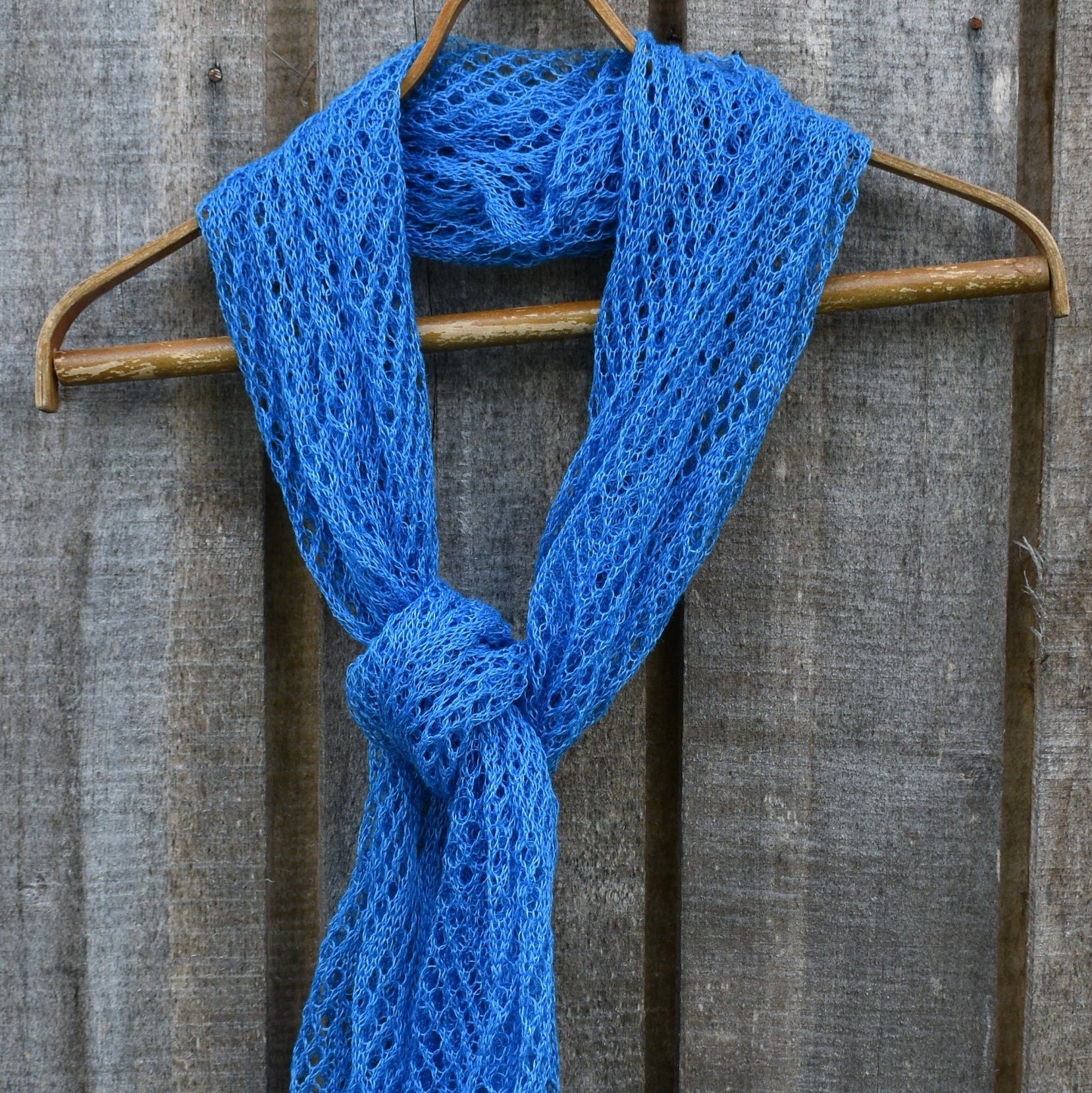 Blue knitted scarf on a wooden hanger against a wooden background