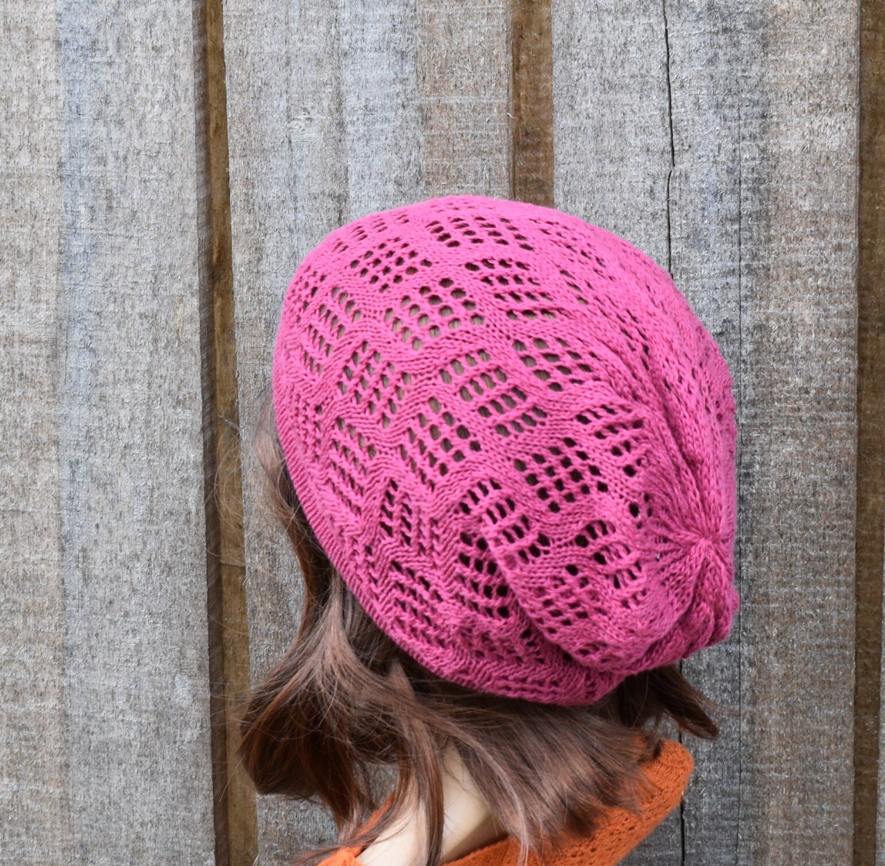 Person wearing a pink knitted hat against a wooden background