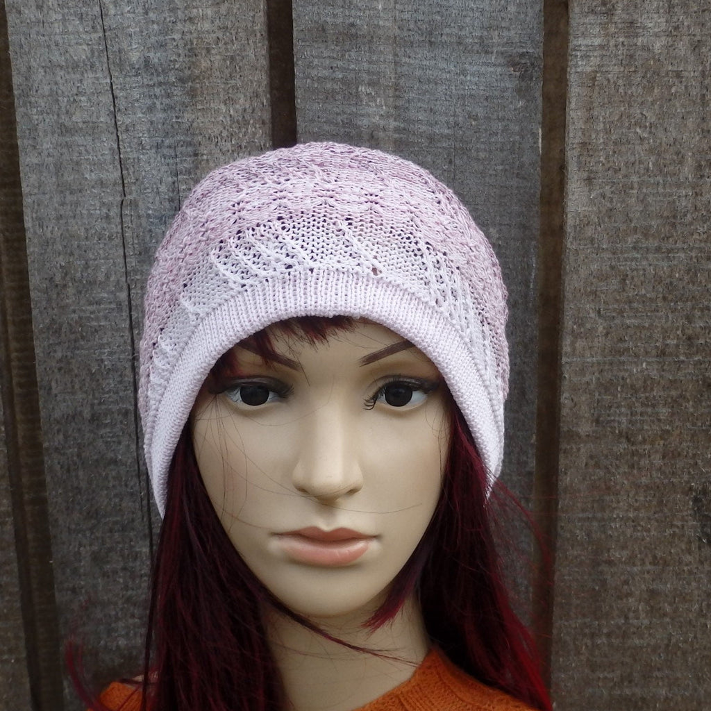 Mannequin head wearing a light purple knitted hat against a wooden background