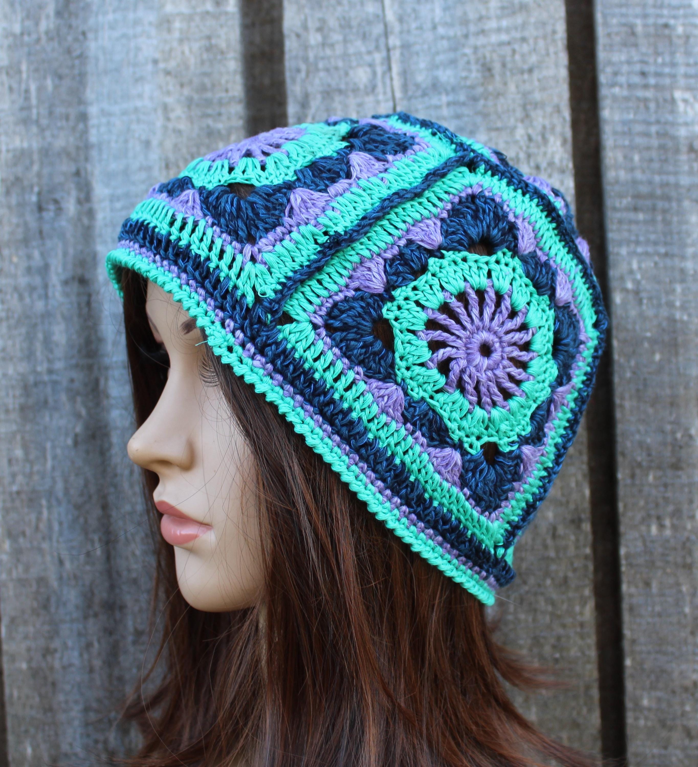 Crocheted beanie with a geometric pattern on a mannequin head against a wooden background
