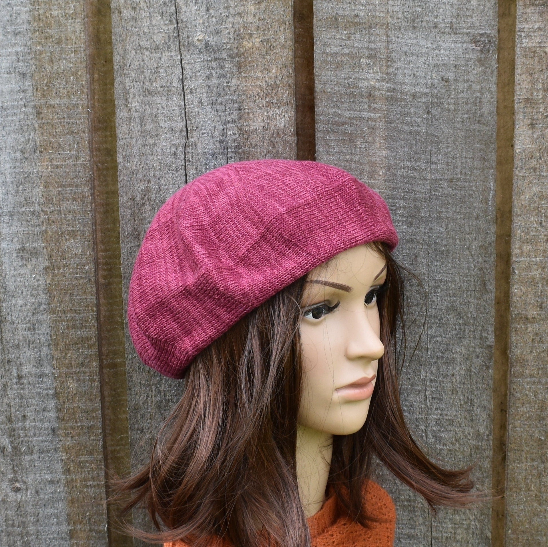 Mannequin head wearing a pink knitted hat against a wooden background