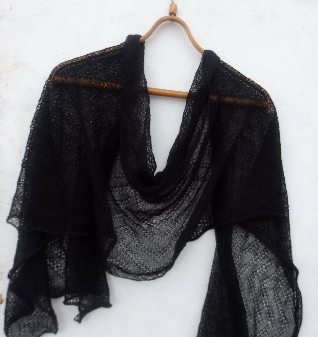 Black shawl draped over a wooden hanger against a white background