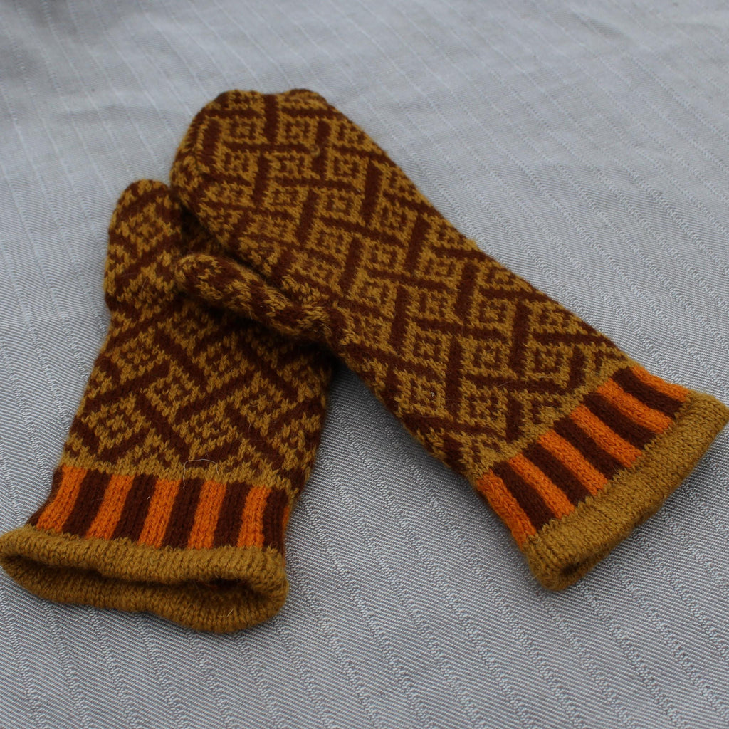 Pair of brown and orange patterned mittens on a gray fabric background