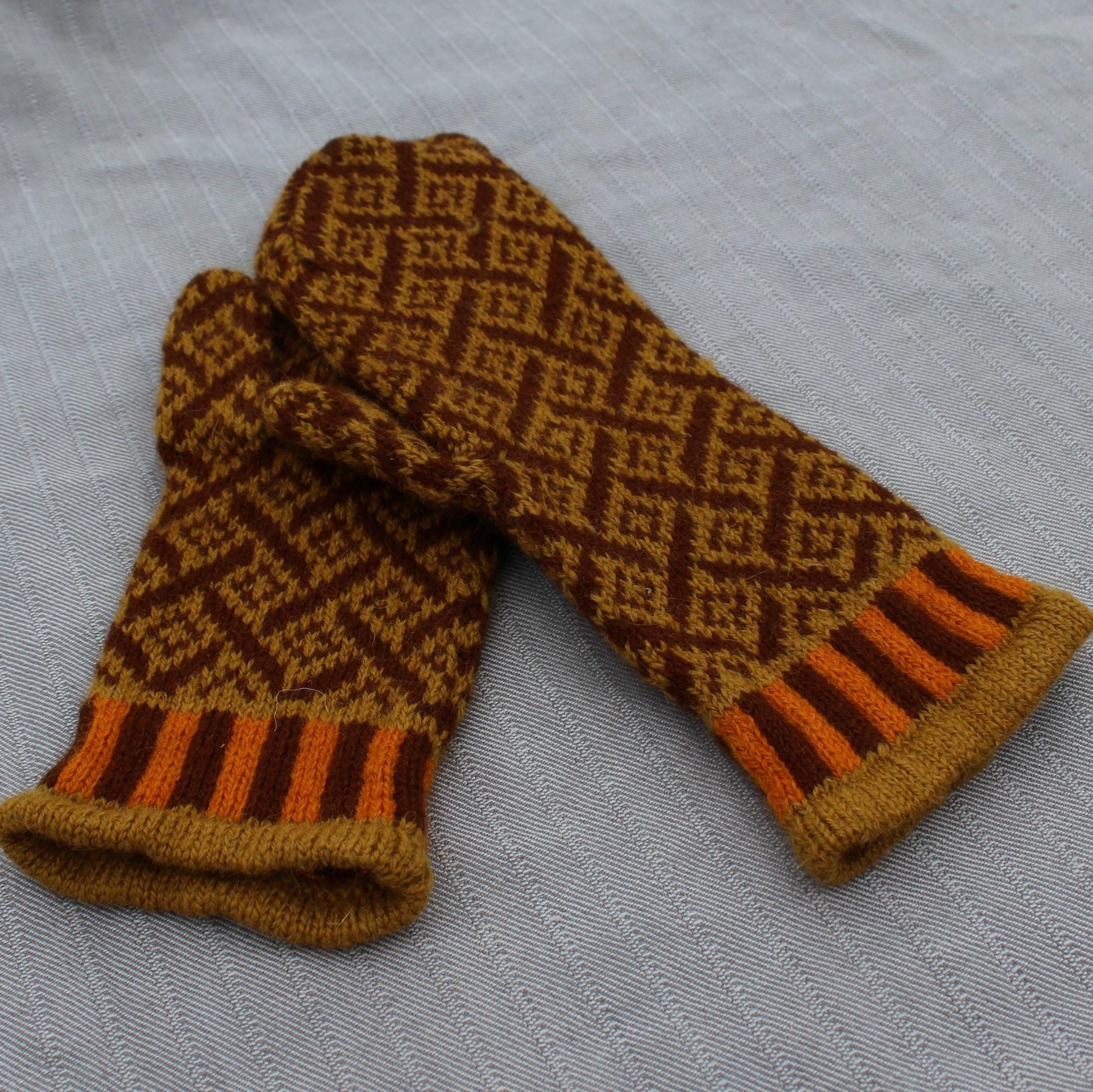 Pair of brown and orange patterned mittens on a gray fabric background
