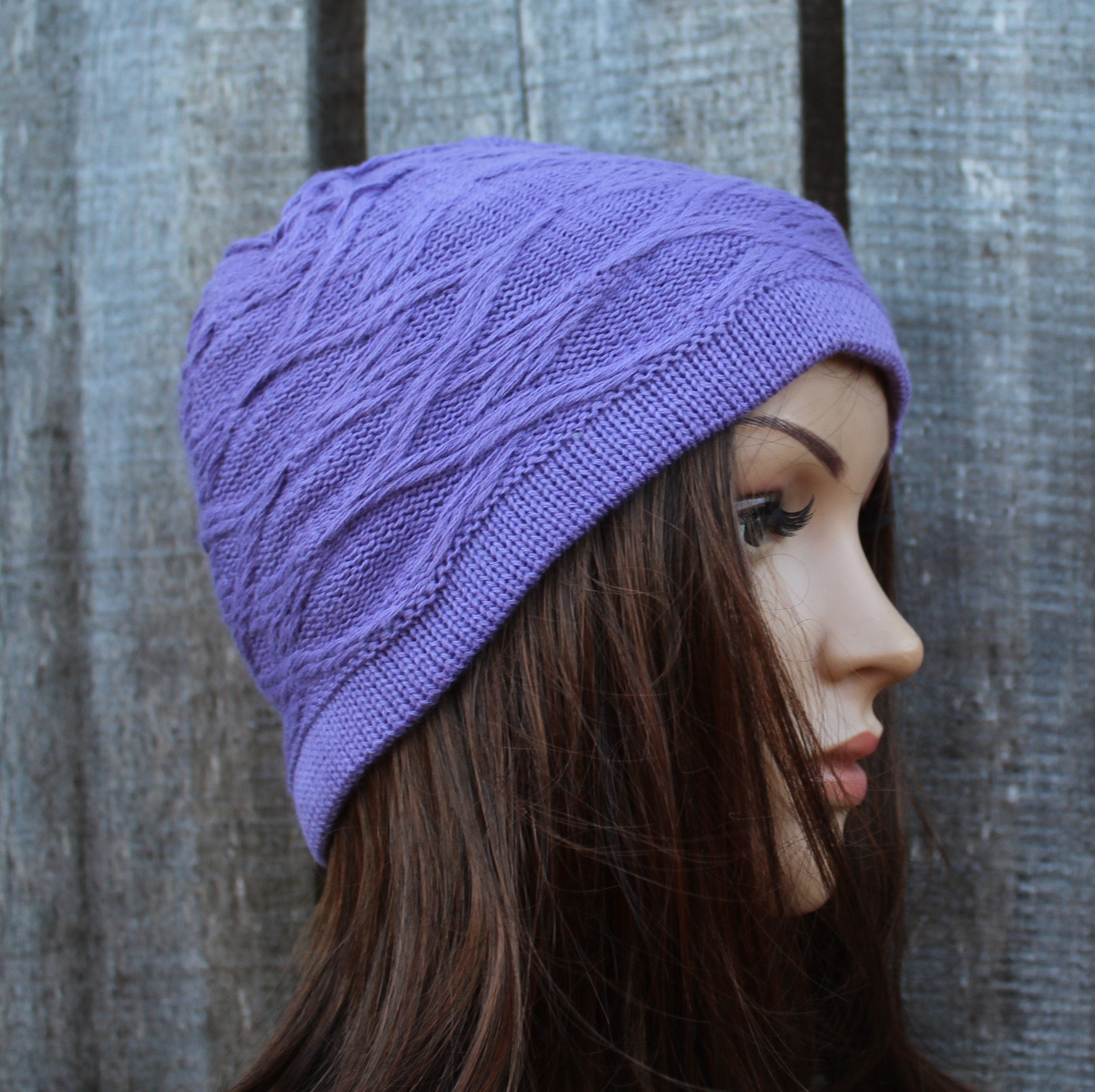 Person wearing a purple knitted hat against a wooden background