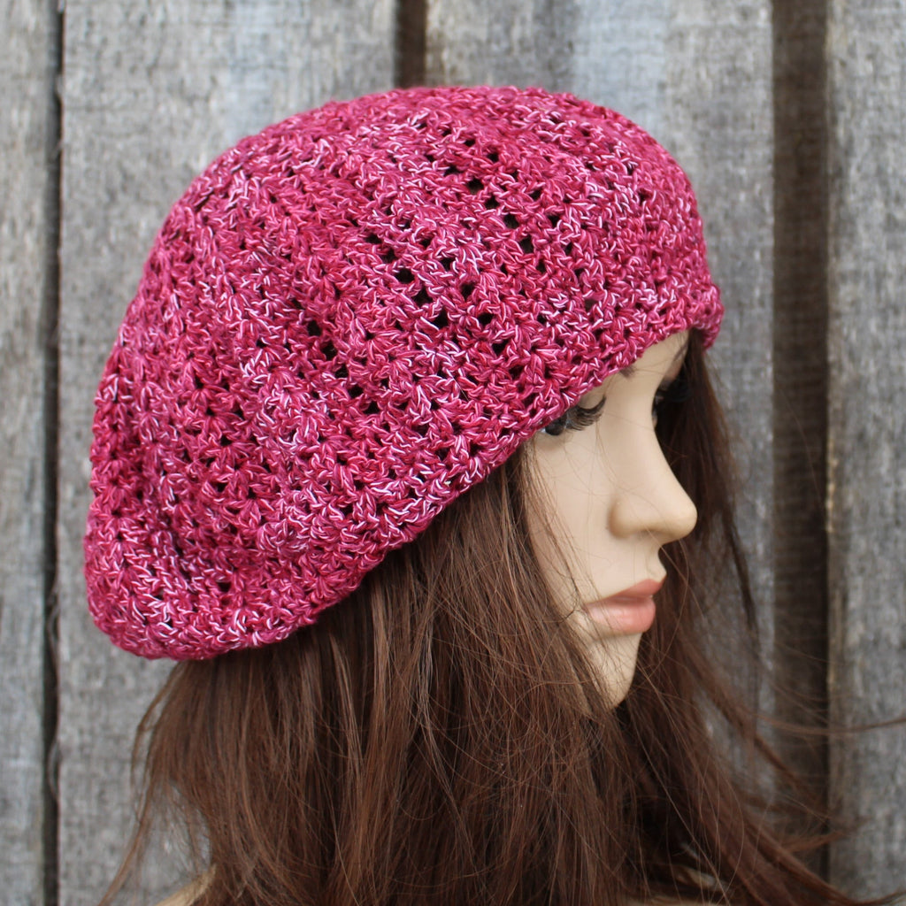 Pink knitted beret worn by a mannequin against a wooden background