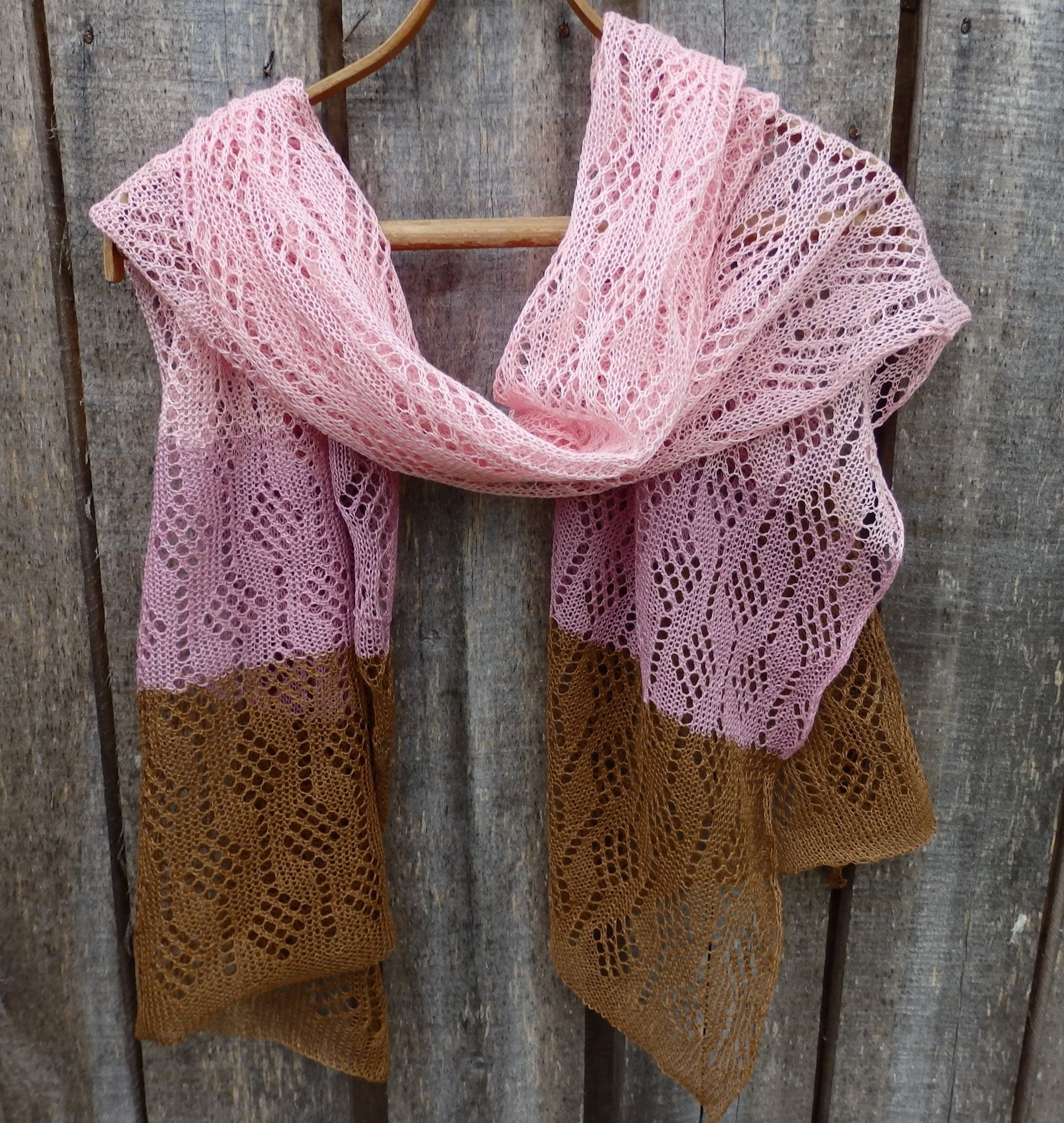 Knitted scarf with pink and brown gradient on a wooden background