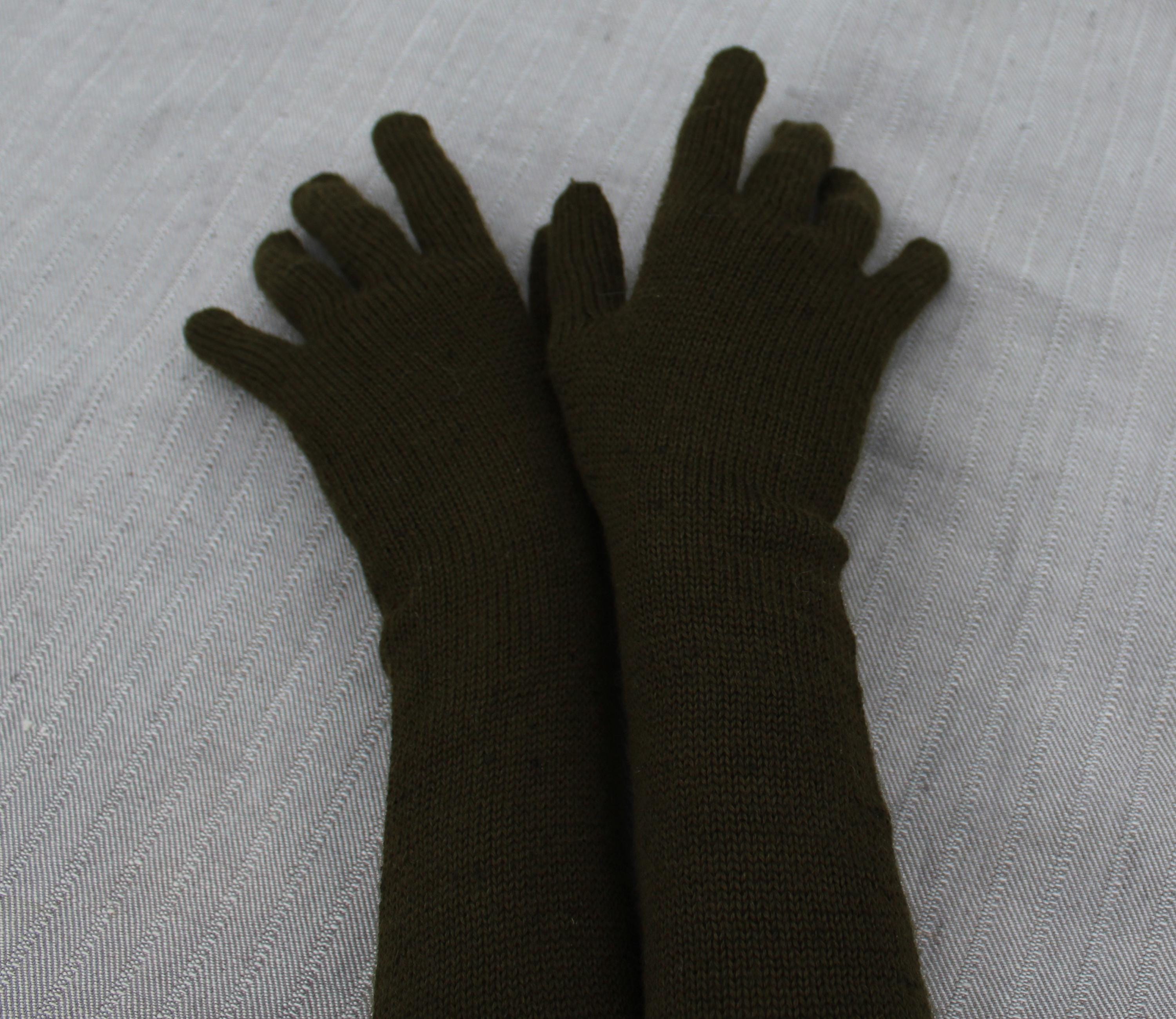 Pair of dark green gloves on a light gray textured surface