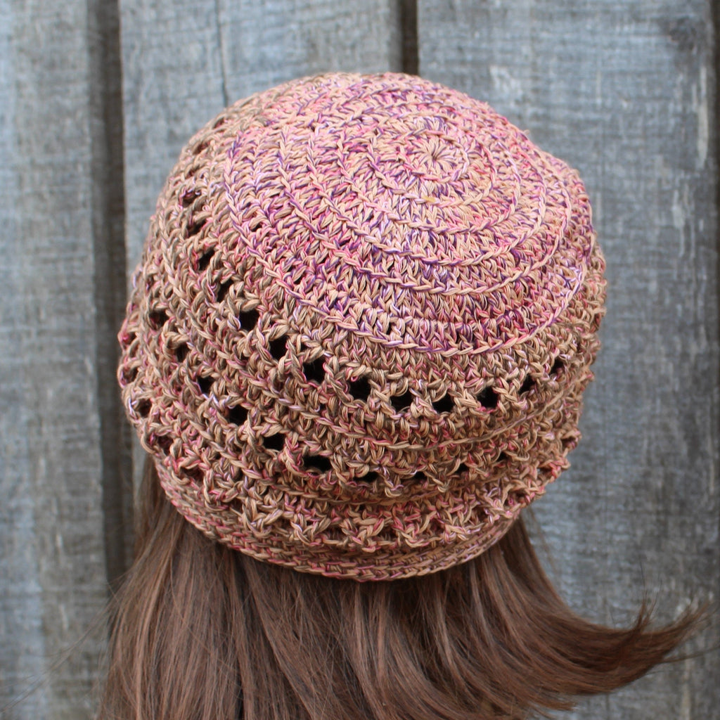 Crocheted hat with a textured pattern worn by a person with long hair against a wooden background