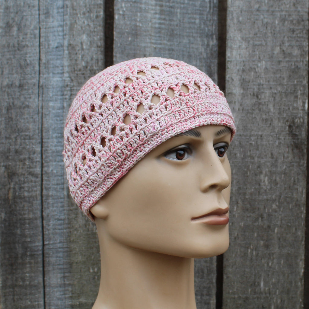 Pink crochet hat on a mannequin head against a wooden background
