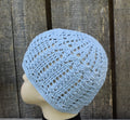 Light blue knitted beanie on a mannequin head against a wooden background