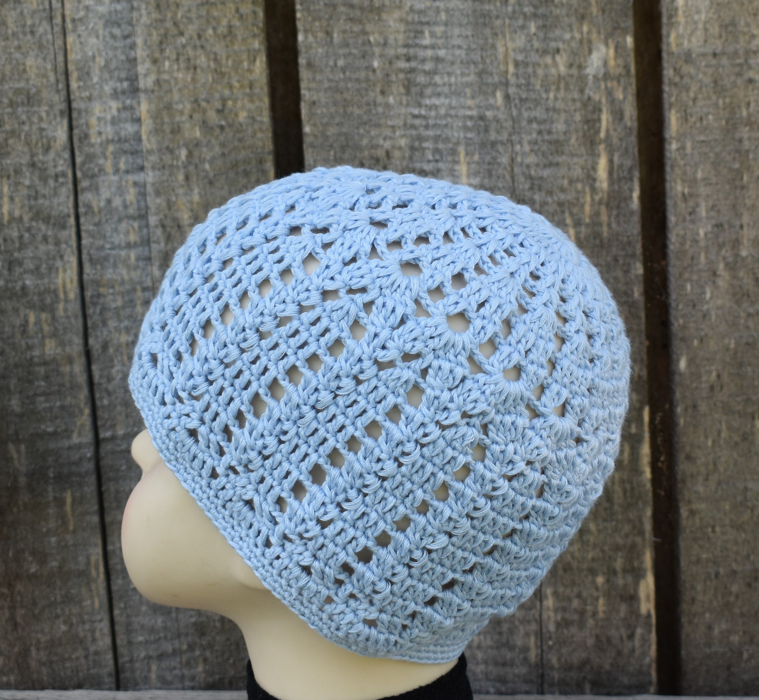Light blue knitted beanie on a mannequin head against a wooden background
