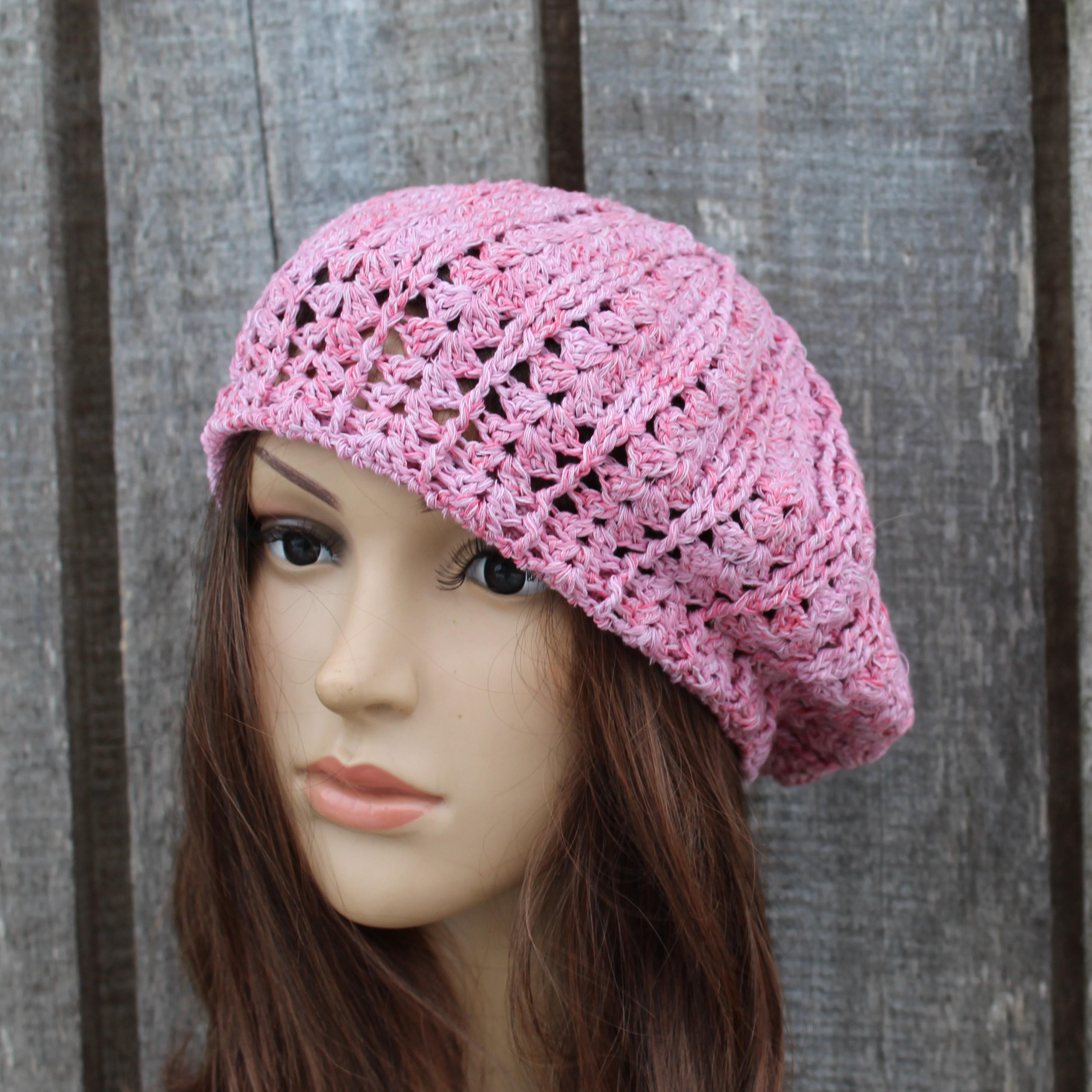 Pink crocheted hat on a mannequin head against a wooden background
