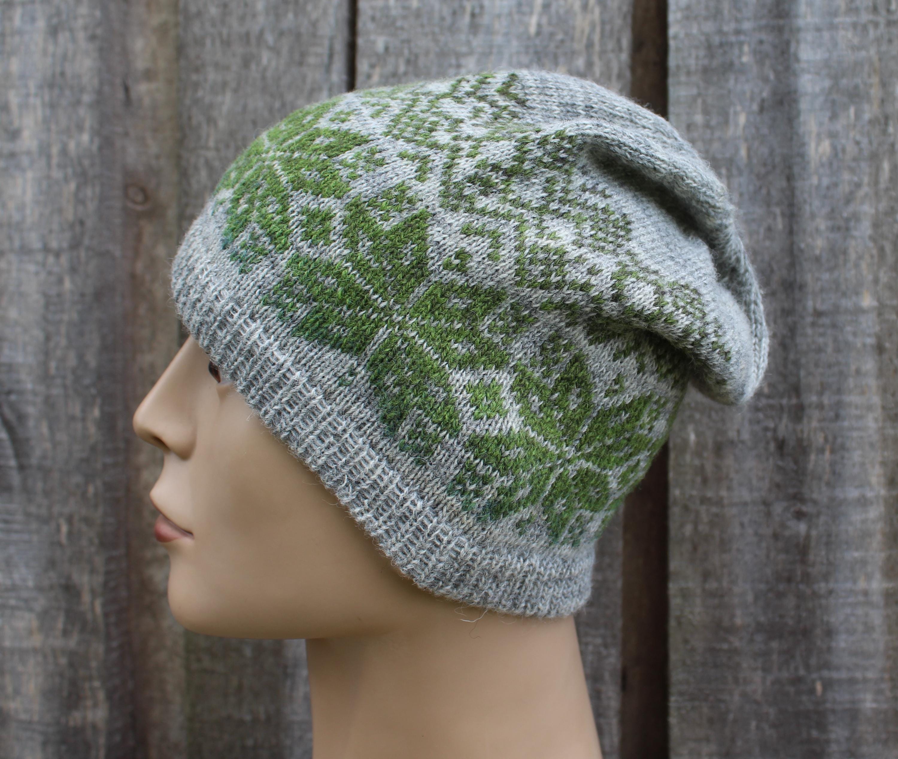 Knitted hat with green and gray pattern on a mannequin head against a wooden background