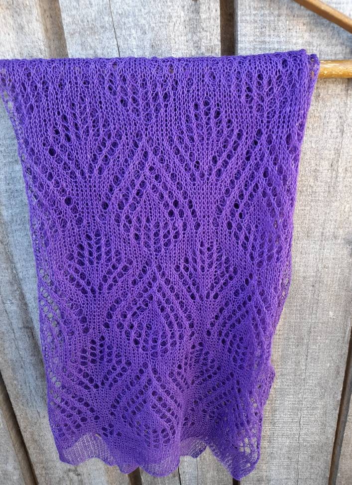 Purple knitted shawl on a wooden surface