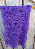 Purple knitted shawl on a wooden surface