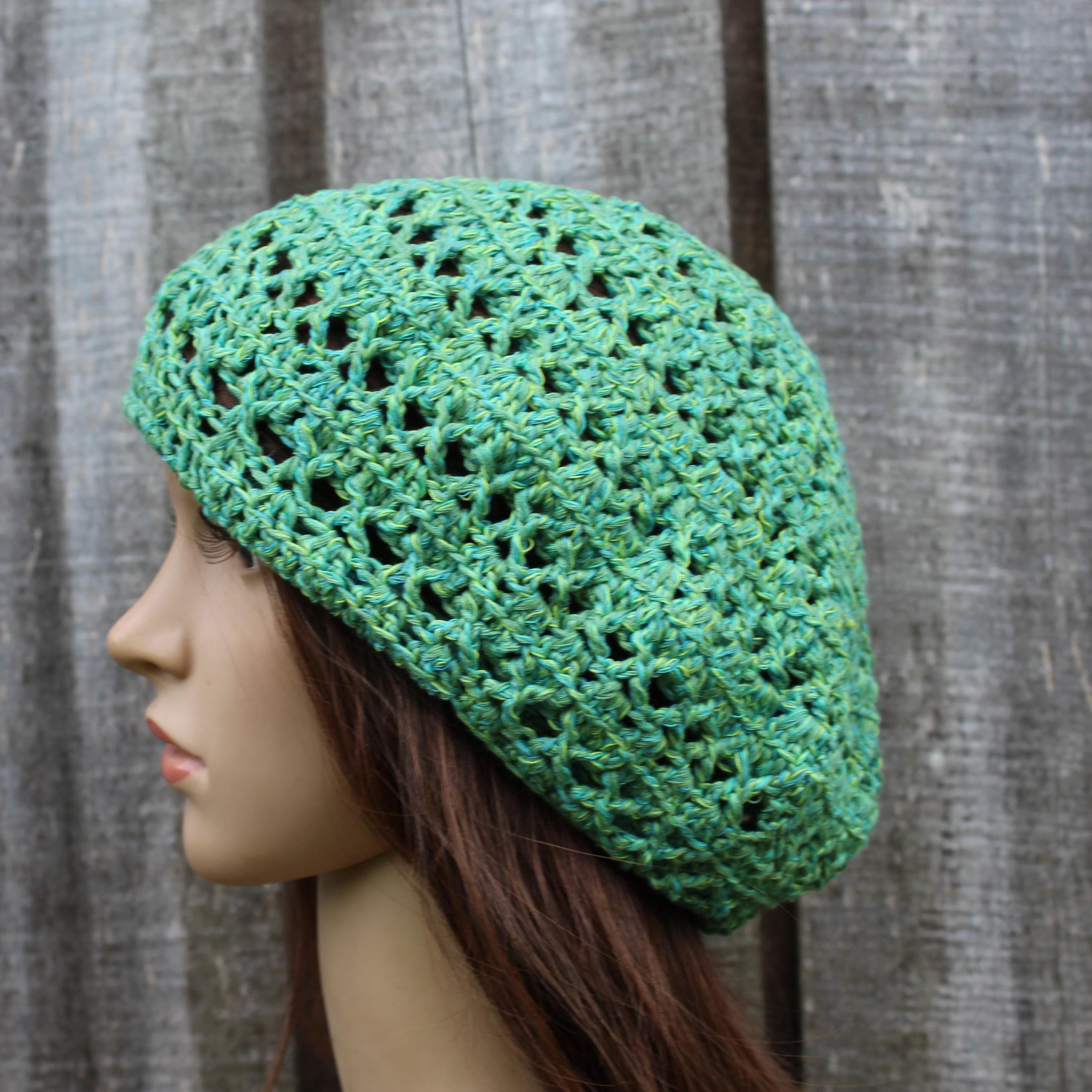 Green crochet hat on a mannequin head against a wooden background