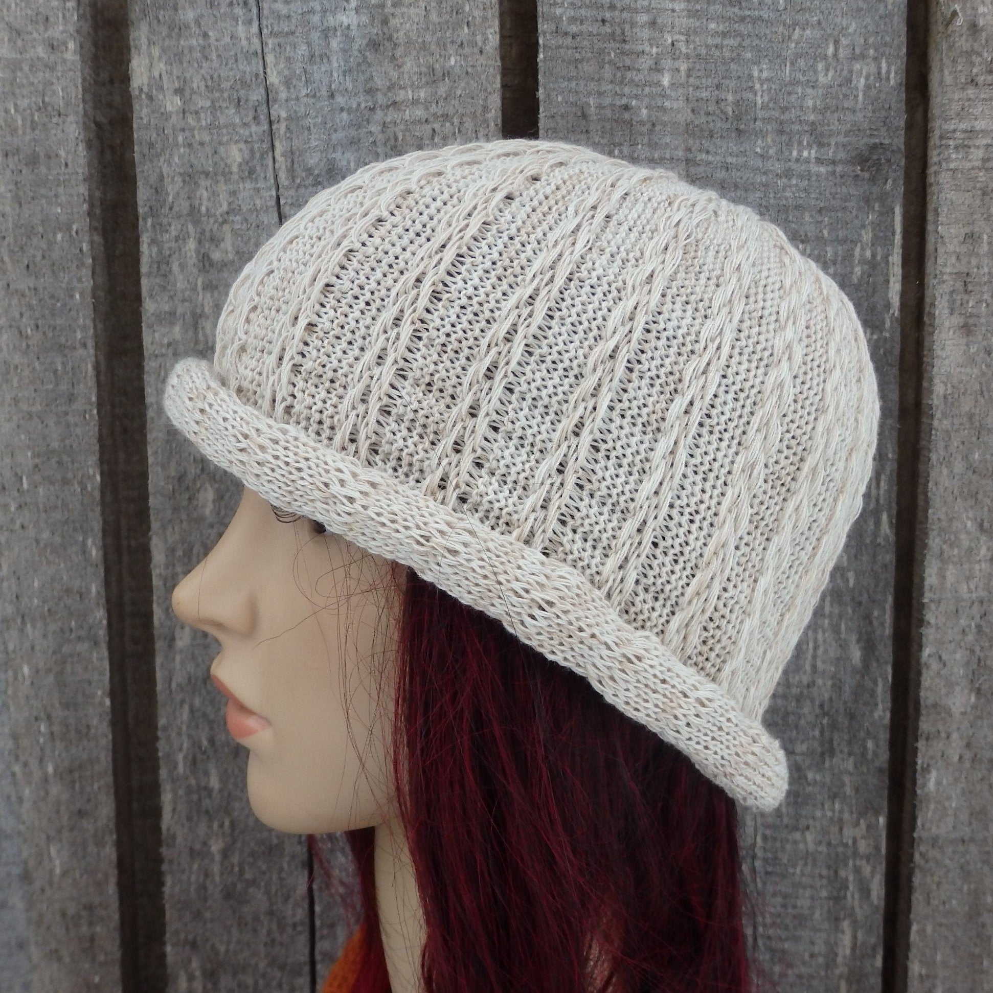 Knitted beige hat on a mannequin head against a wooden background