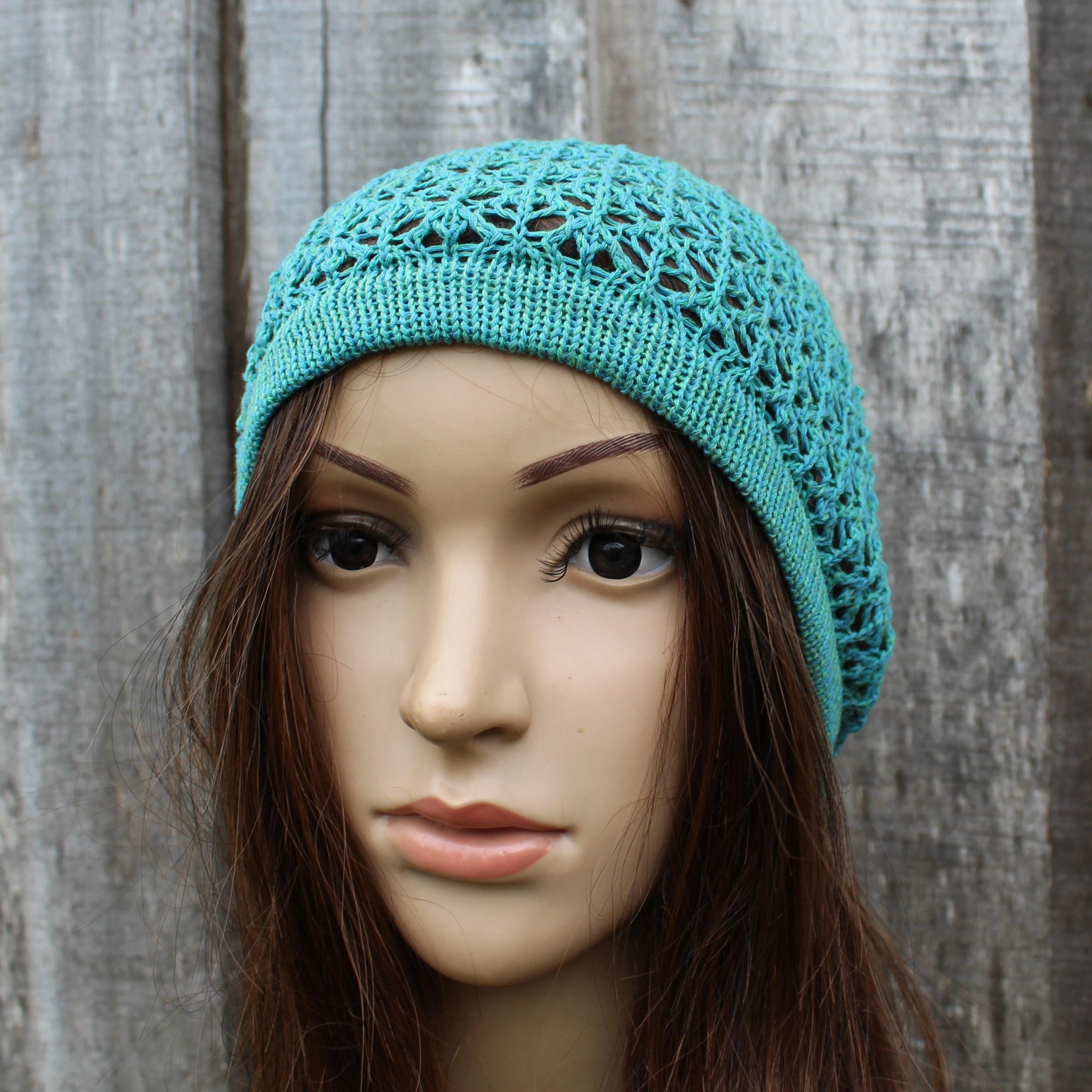 Teal knitted hat on a mannequin head against a wooden background