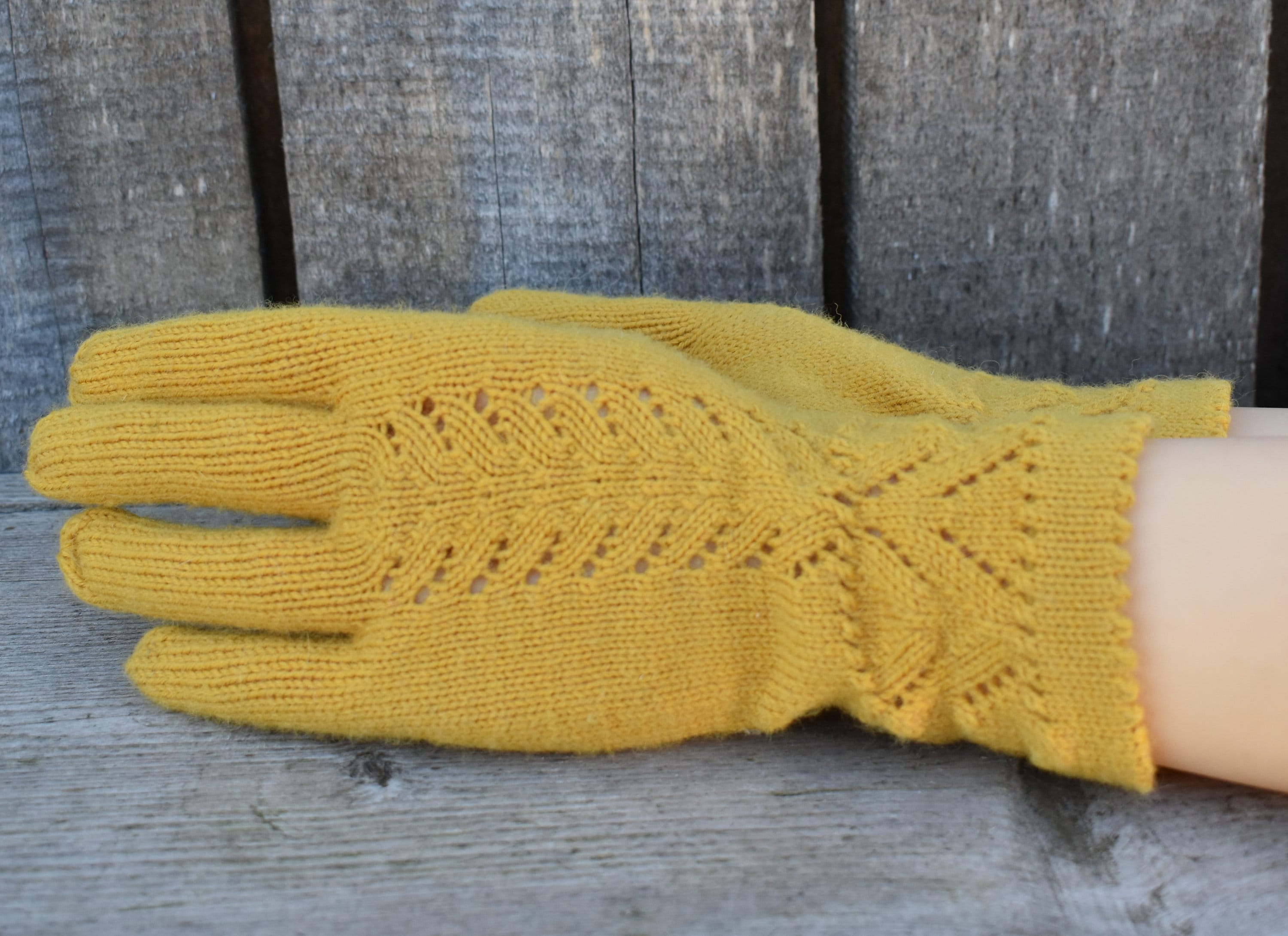 Yellow knitted glove on a wooden surface