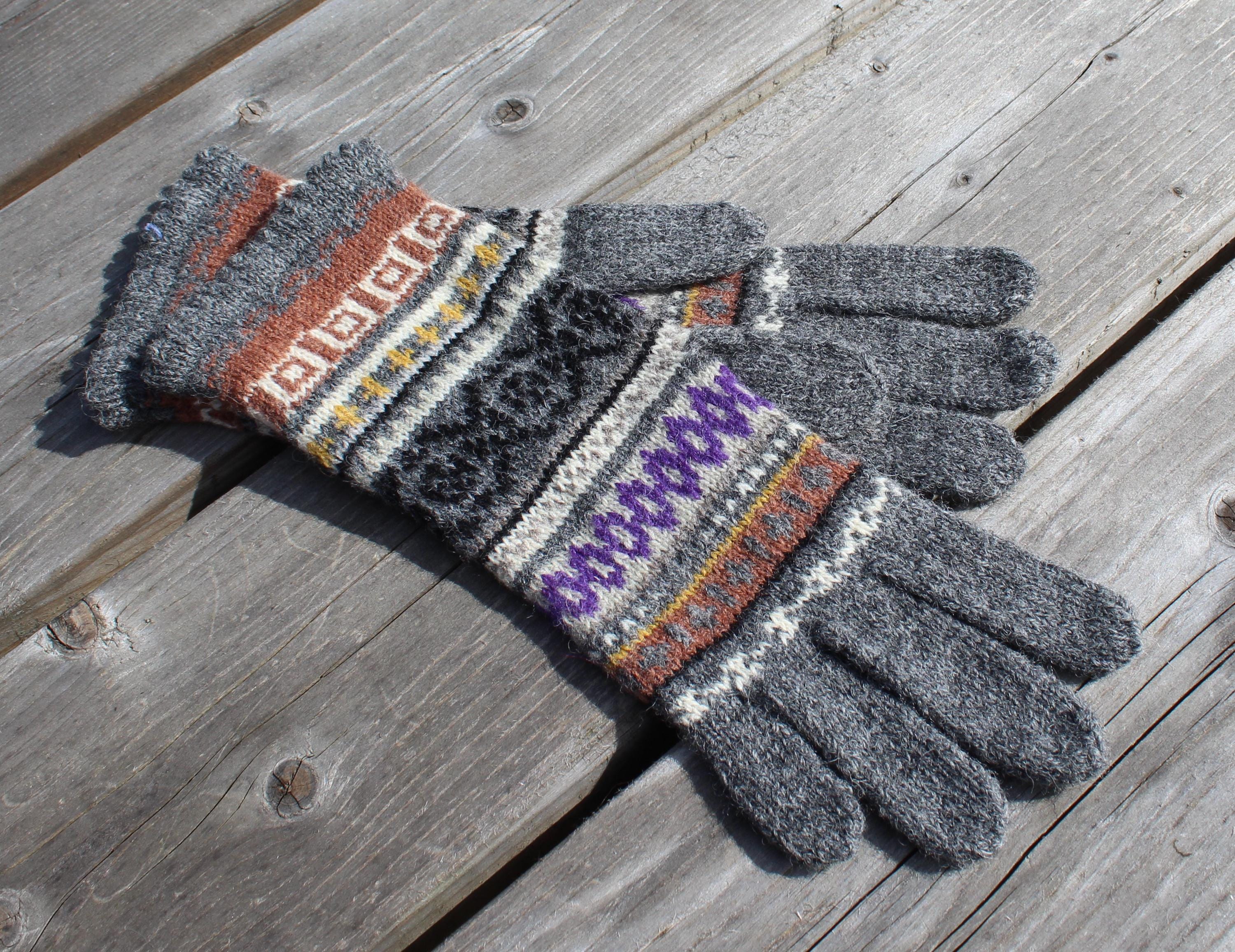 Pair of gray gloves with patterned cuffs on a wooden surface
