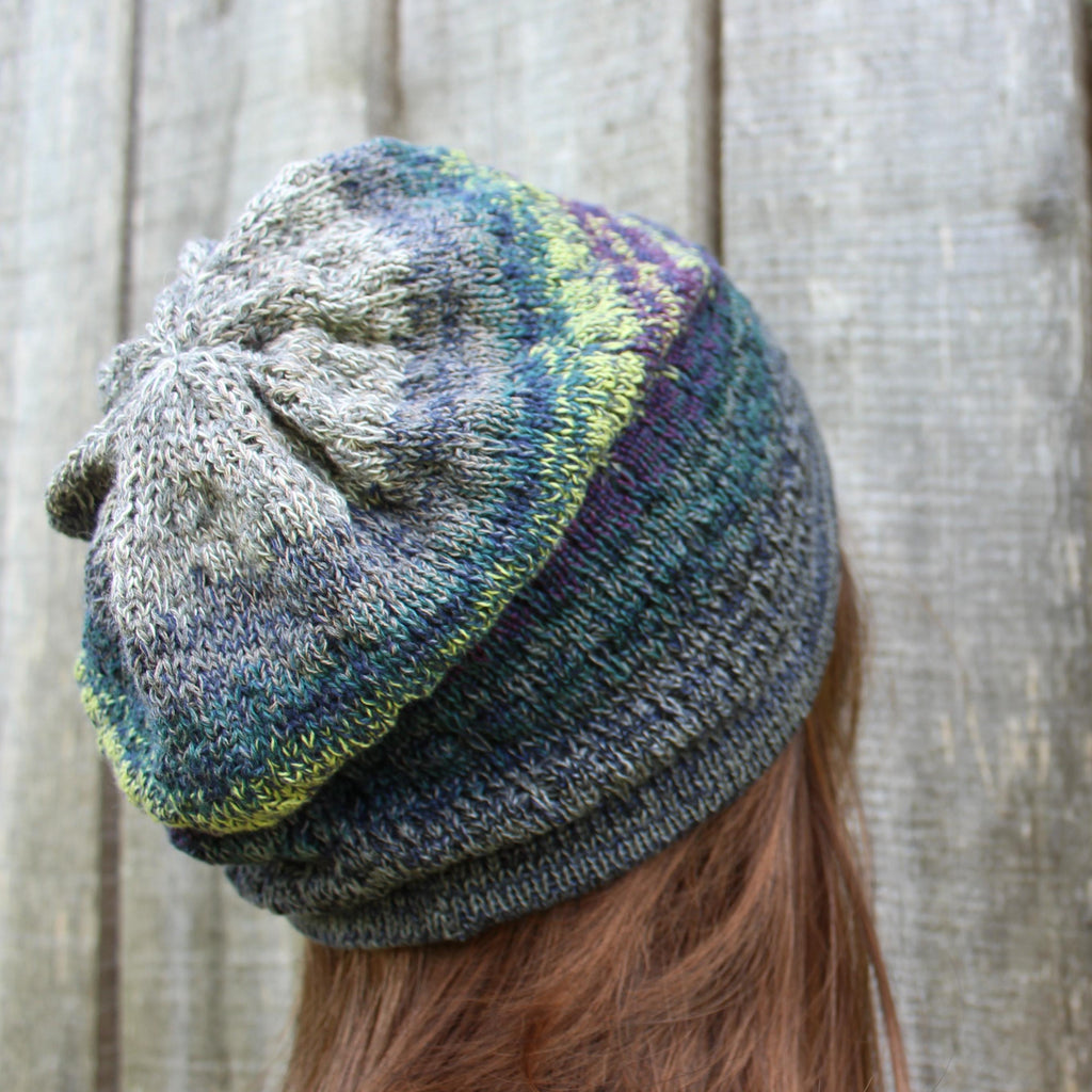 Multicolored knit beanie worn by a person with a wooden background