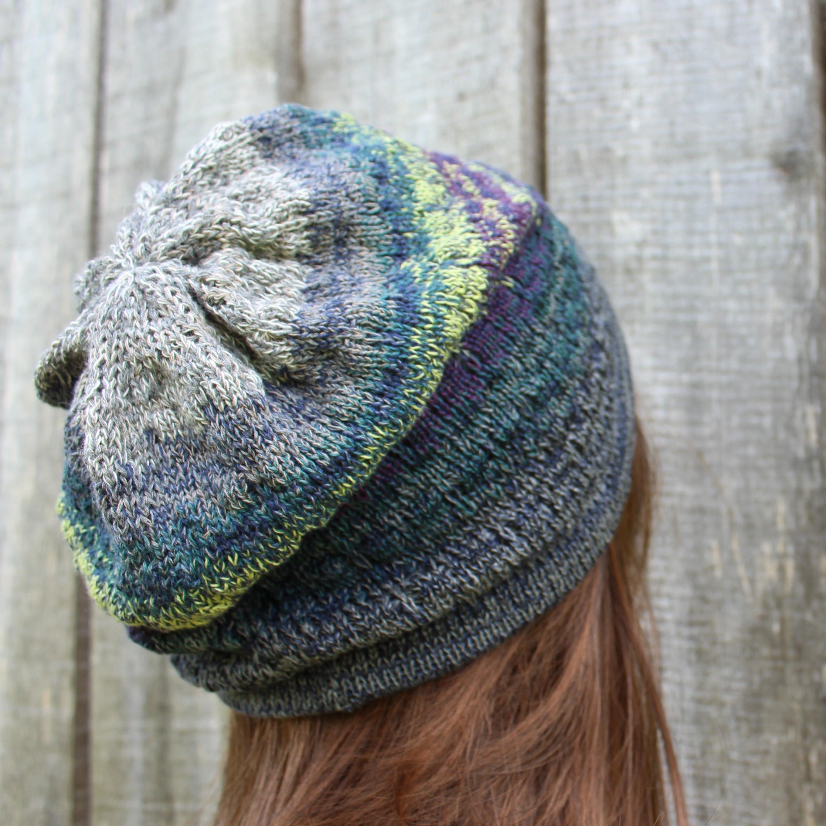 Multicolored knit beanie worn by a person with a wooden background