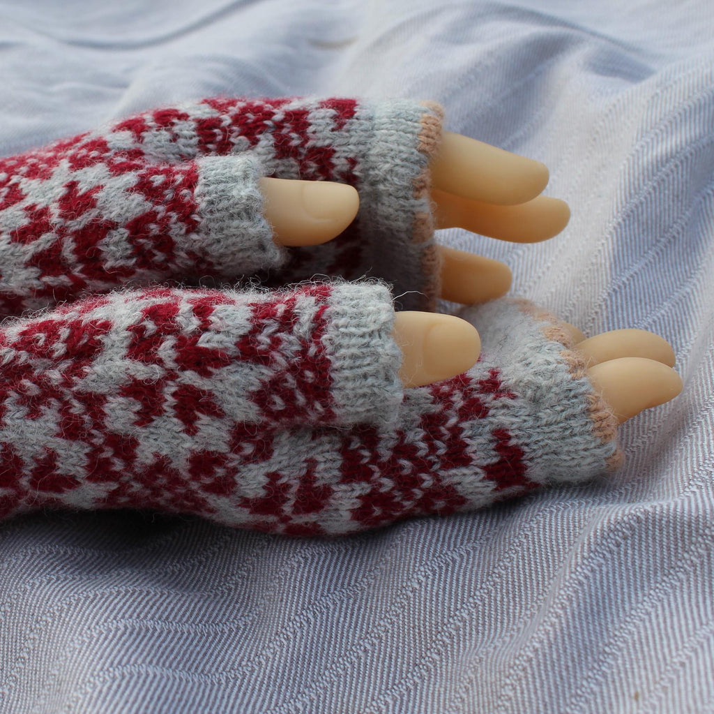 Pair of knitted fingerless gloves with a pattern on a fabric background