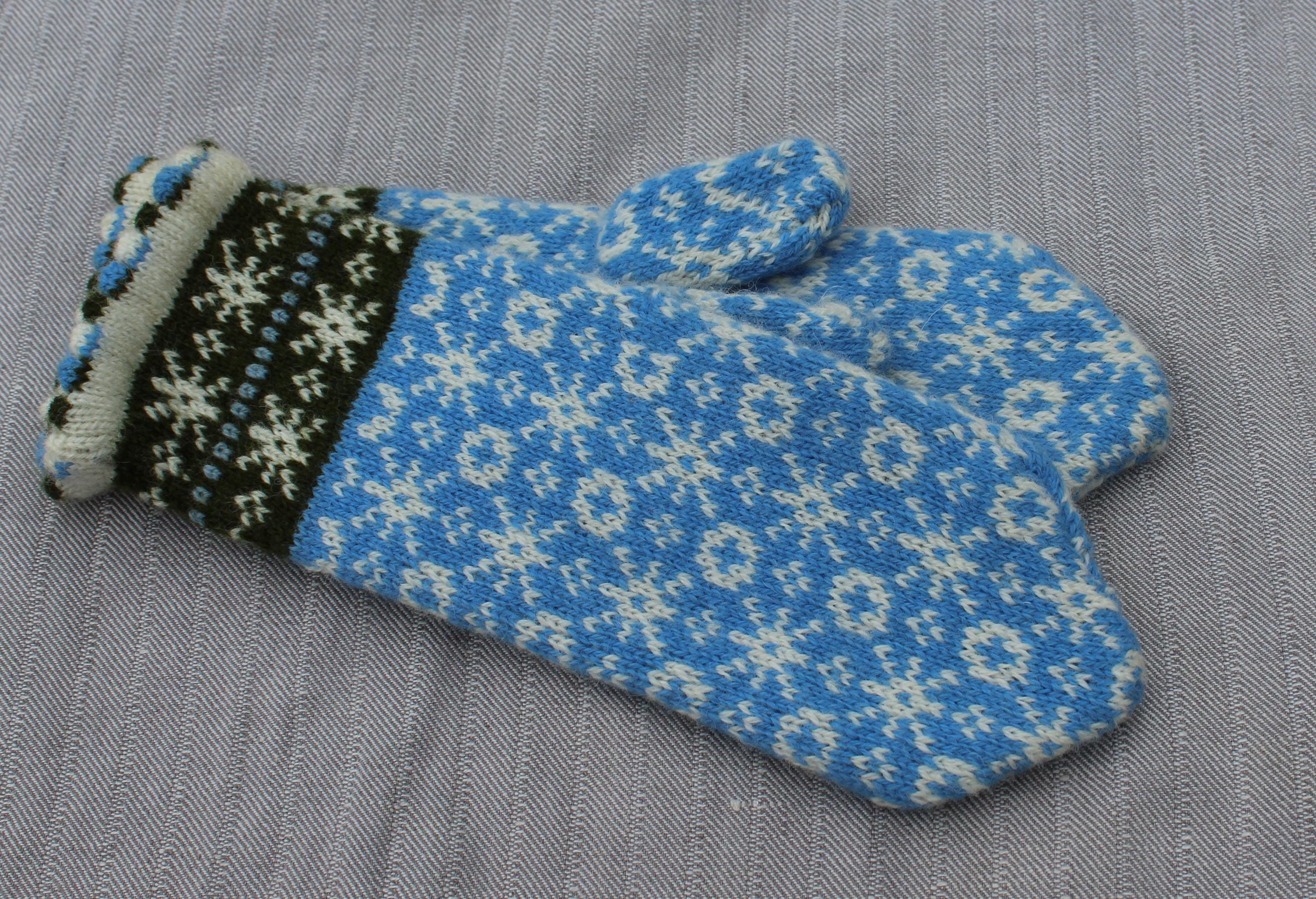 Blue knitted glove with white snowflake pattern on a gray background