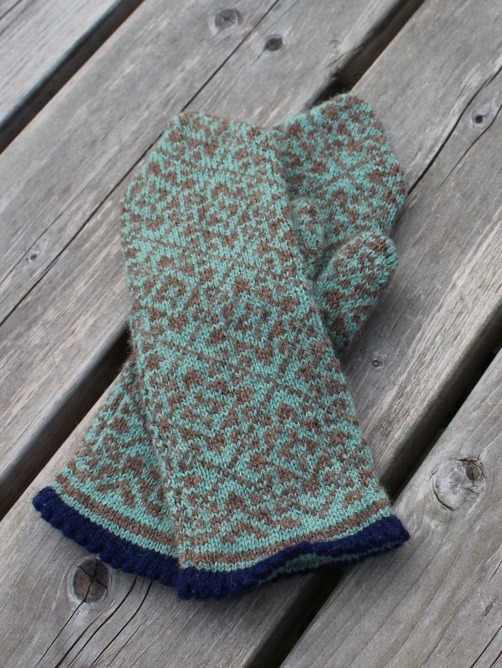 Knitted mittens with a pattern on a wooden surface