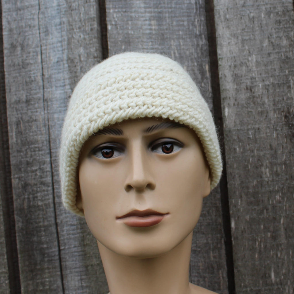 Mannequin head wearing a cream knitted beanie against a wooden background