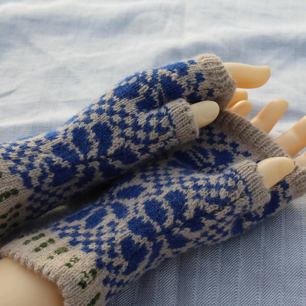 Pair of blue and beige patterned fingerless gloves on a mannequin hand against a light fabric background.