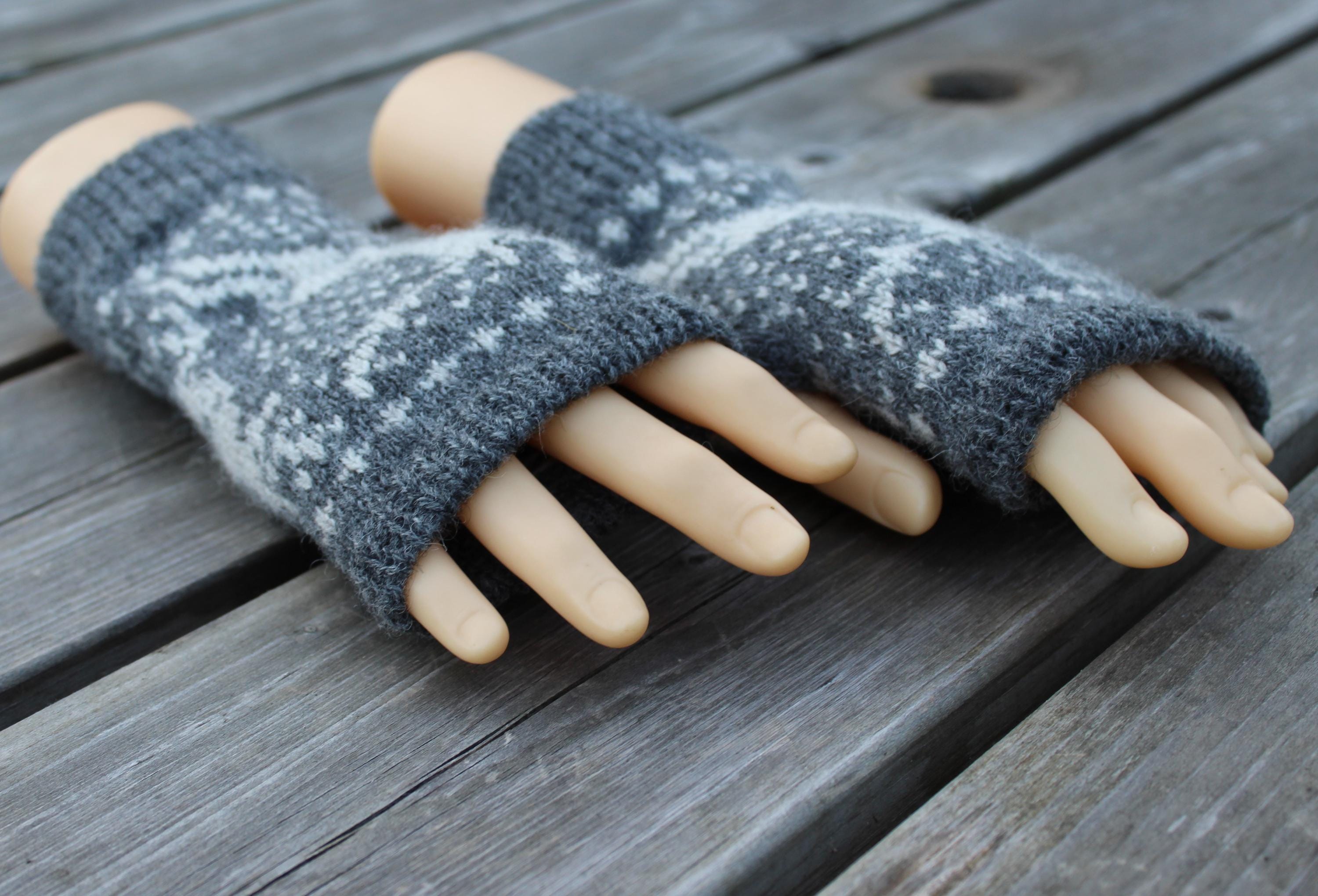 Gray fingerless gloves with white pattern on a wooden surface